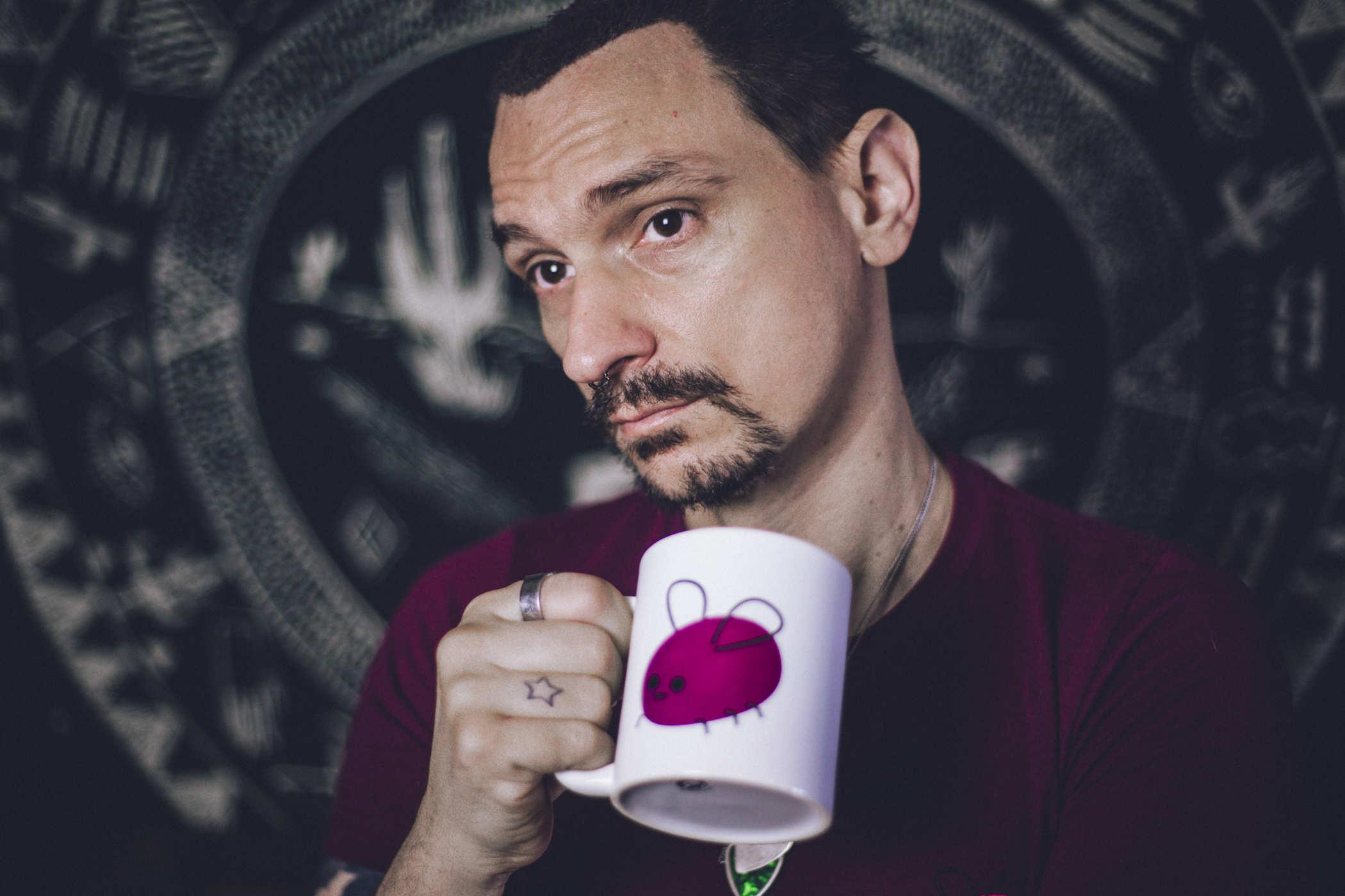 Photo of a me wearing a purple shirt, holding up a white coffee mug with Cohost.org's mascot, Eggbug on it