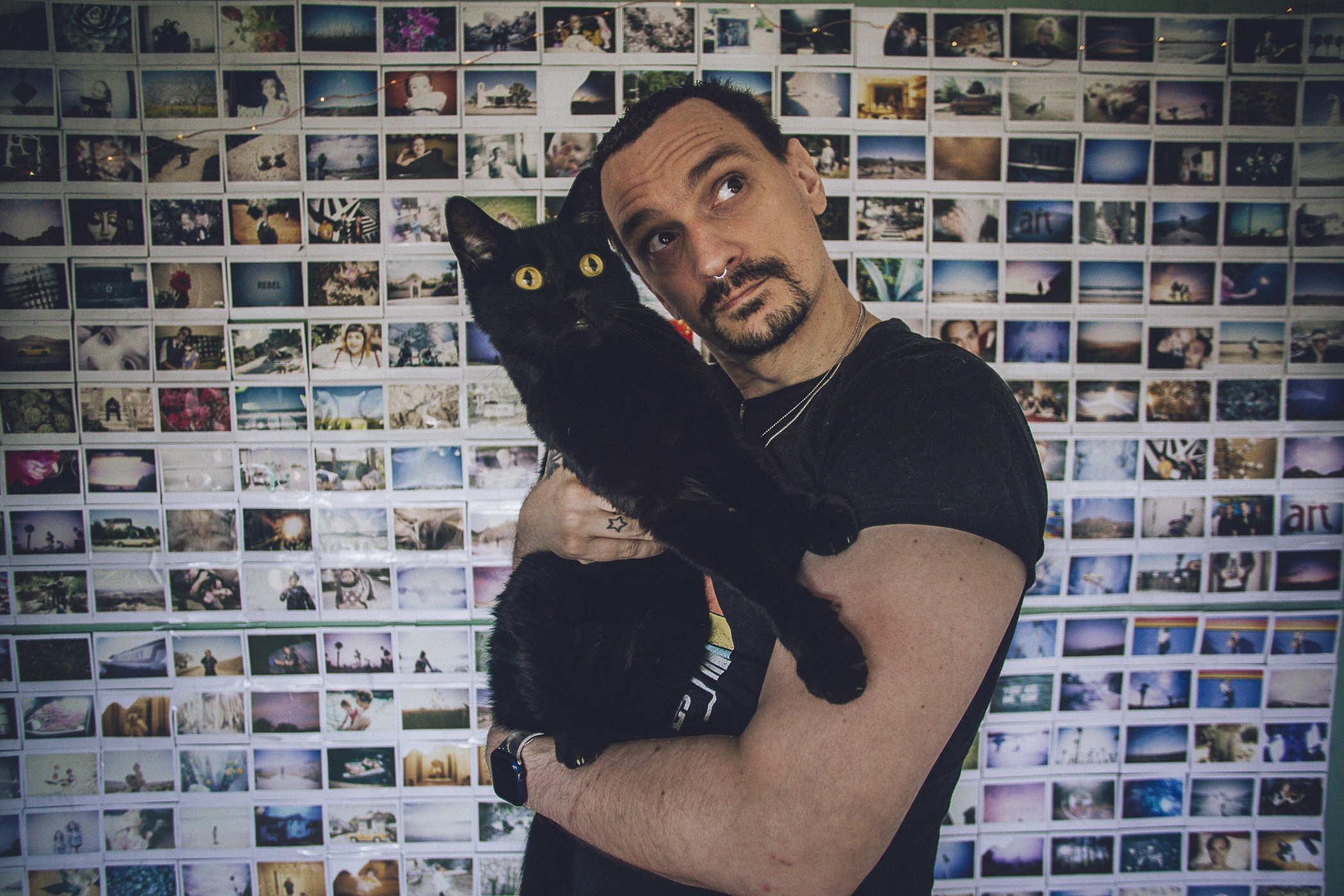 Same as above but now I'm holding a black cat with intensely wide eyes; we're both staring up to the camera's right