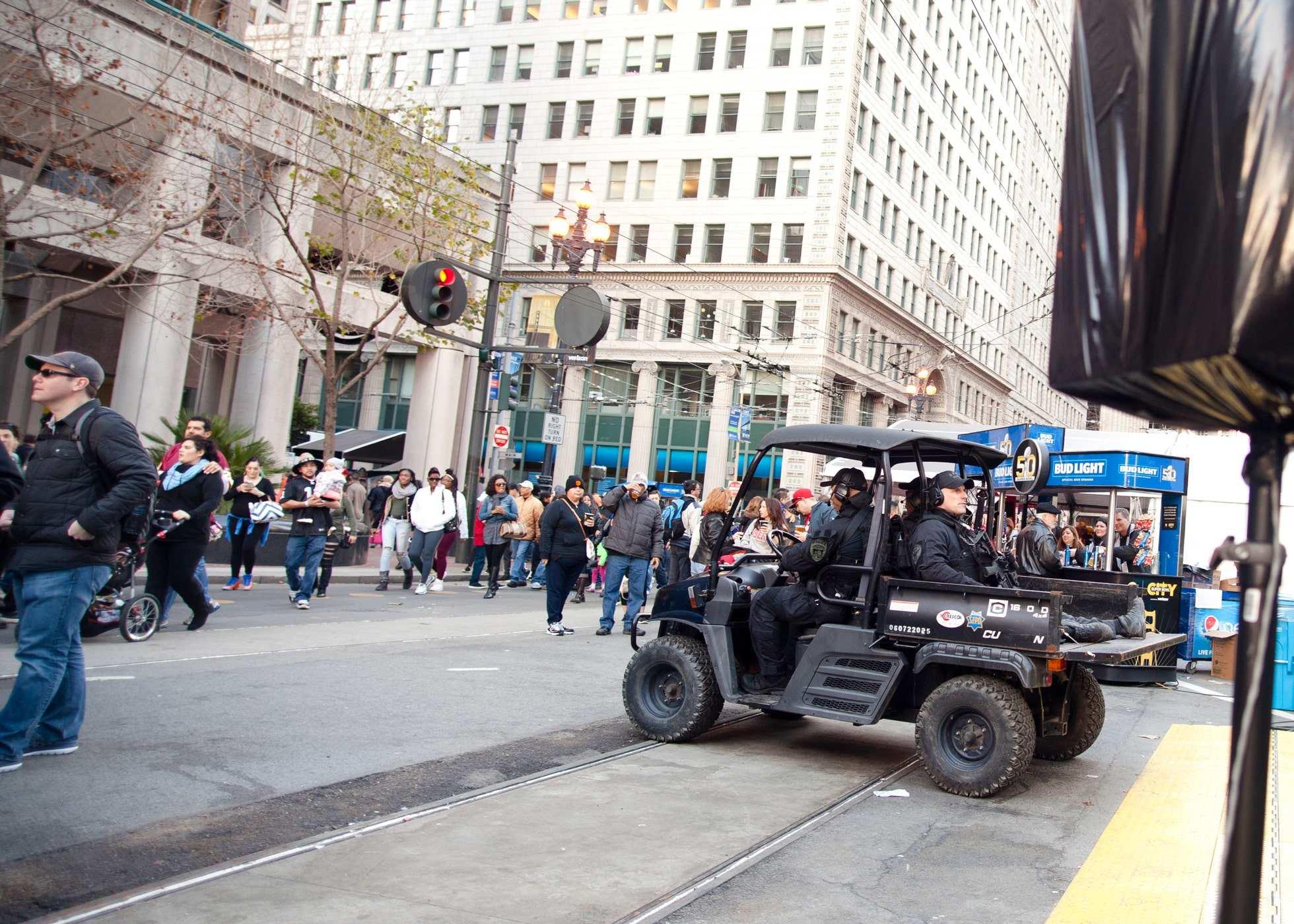 Photo of crowds of people with police wearing military grade gear rolling by on a cart