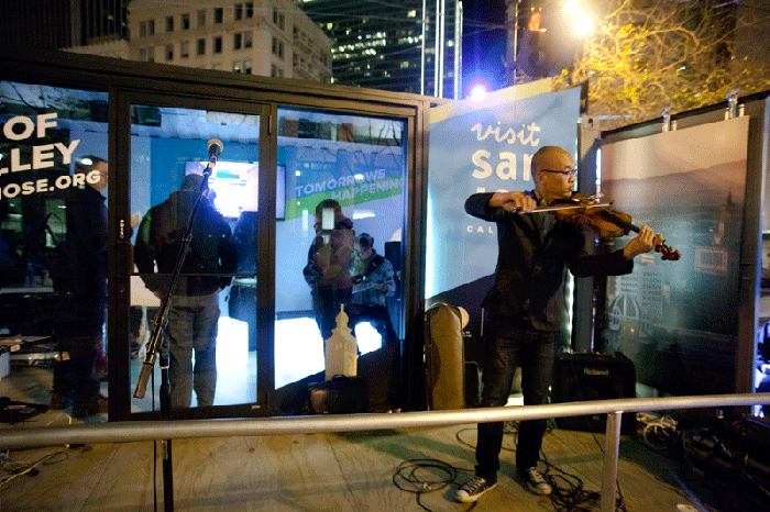 Animated gif of a violinist standing on the side of a stage area and playing