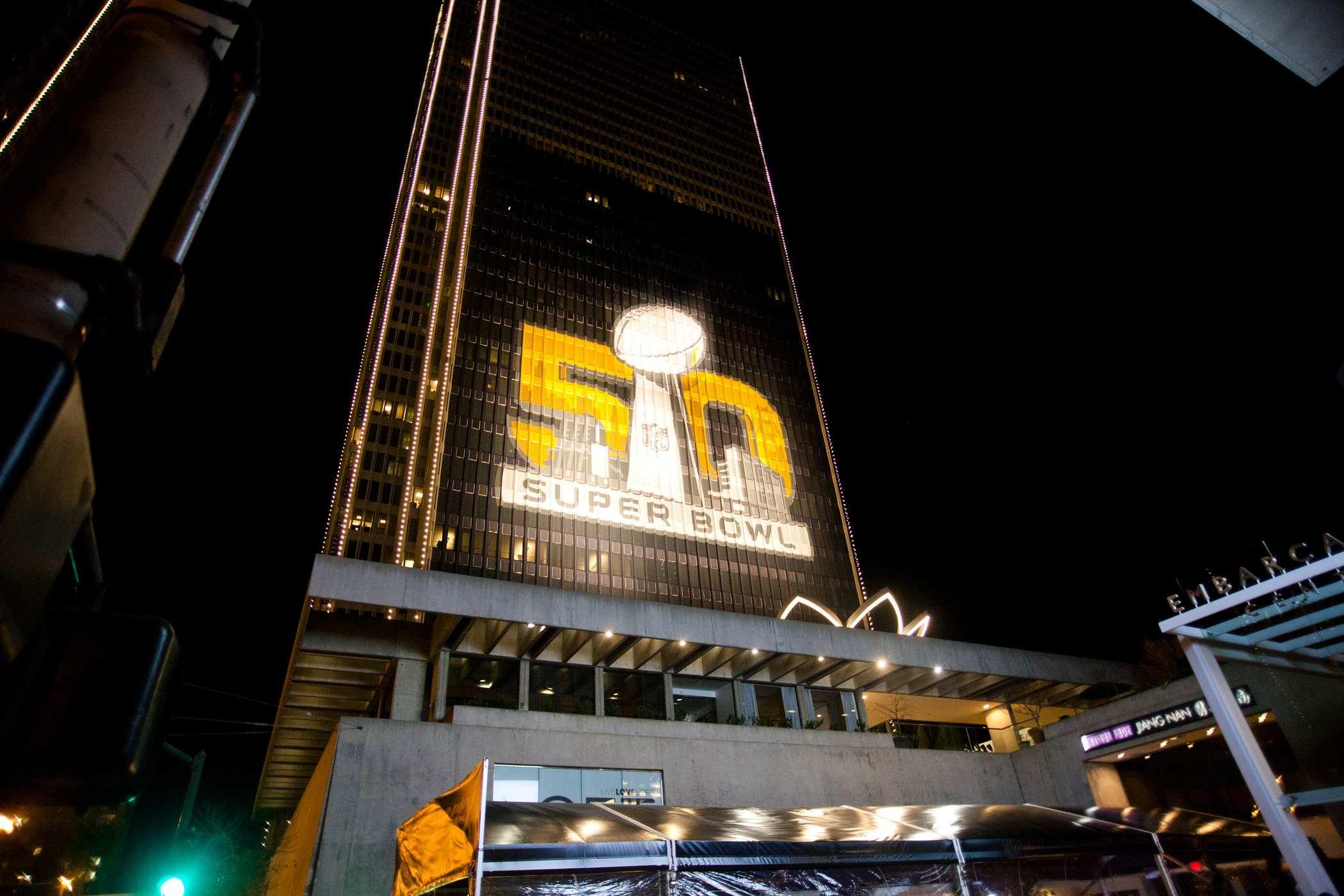 A large light-up sign projected on a skyscraper with the 'Super Bowl 50' logo. 