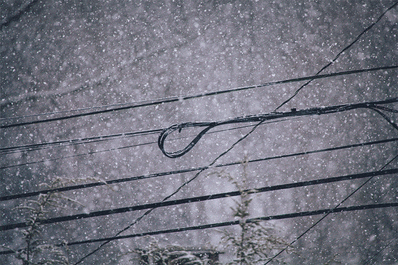 Photo of snow falling around power lines with one of the looped coils at the center