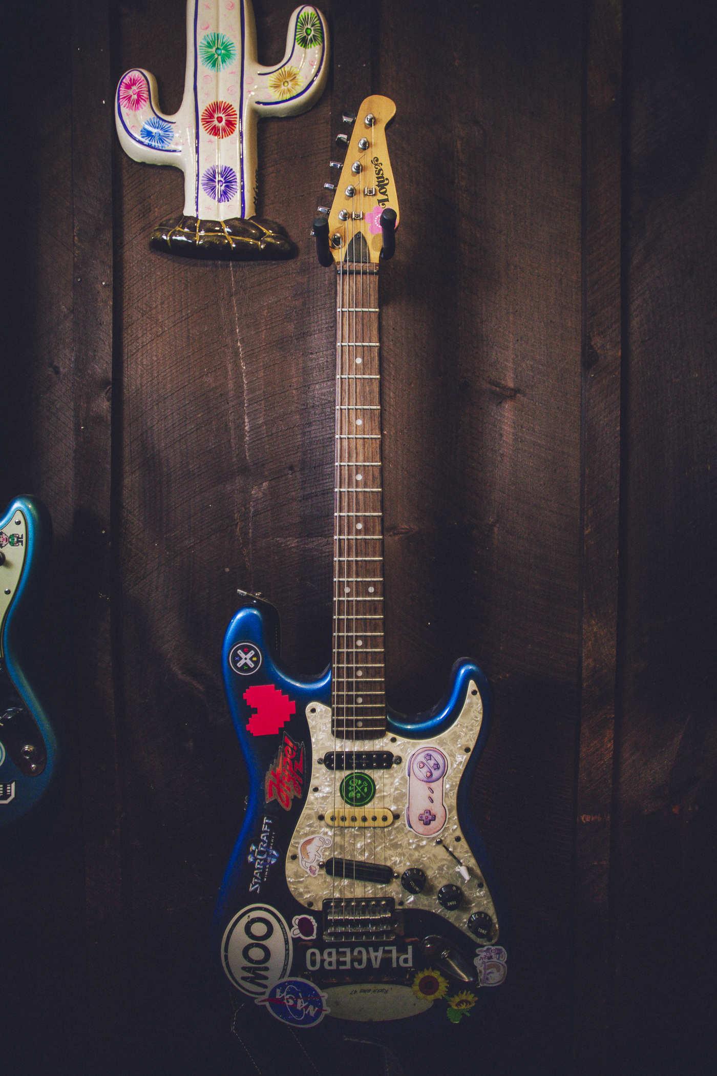 Full view of the guitar hanging from a wooden wall