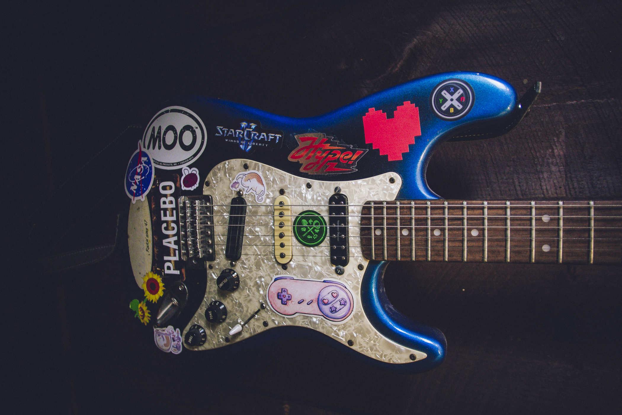 Photo of a blue electric guitar covered in stickets