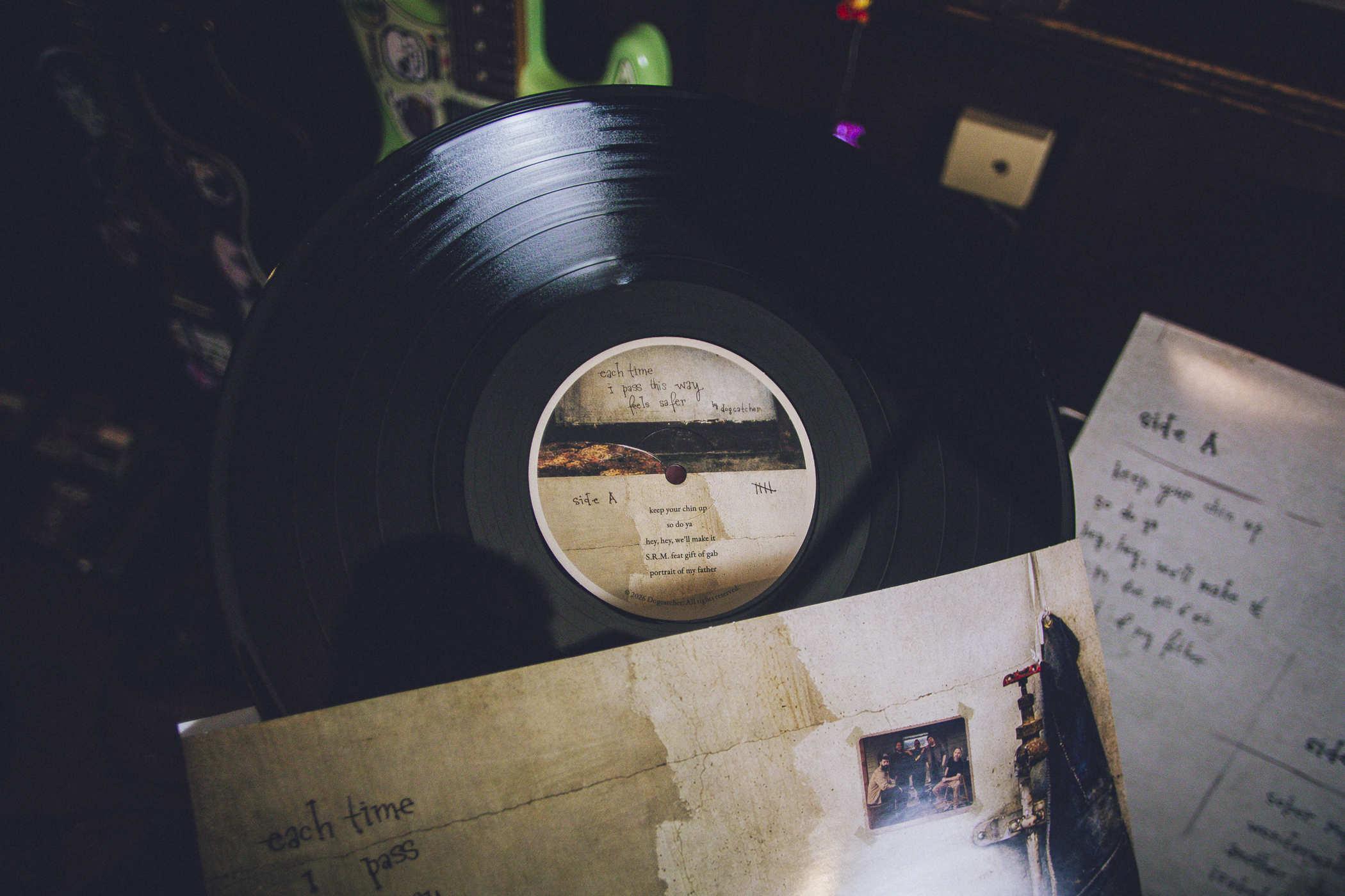 Photo of the record itself coming out of the case; side A contains 'keep your chin up', 'so do ya', 'hey, hey, we'll make it', 'S.R.M. featuring Gift of Gab', and 'portrait of my father'