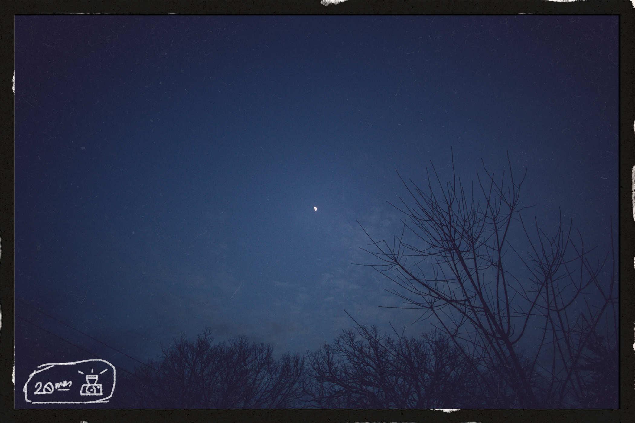 Photo of the night sky with a tiny white dot in the center; handwritten in the lower left is the words '20mm' and a badly drawn camera
