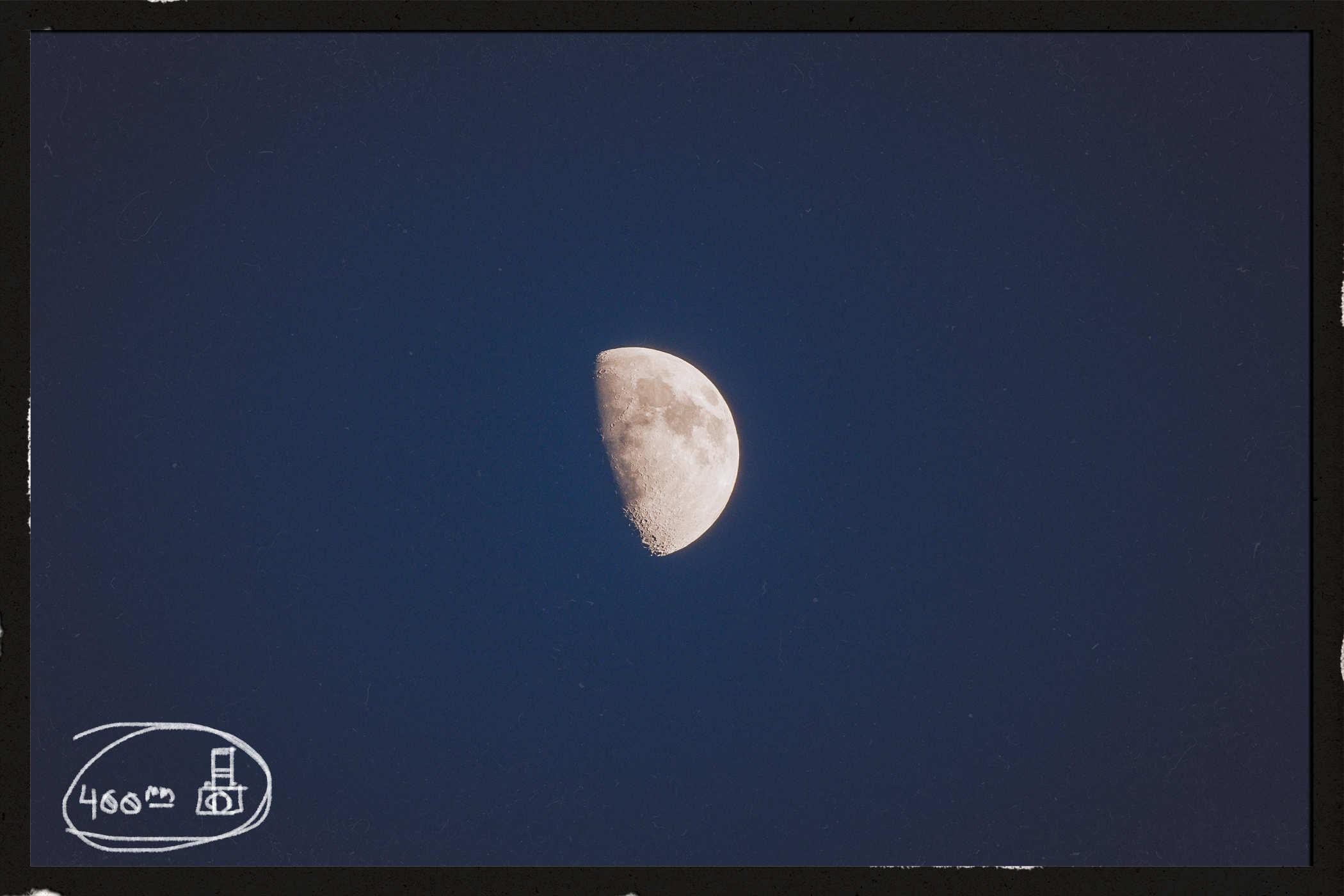 Photo of a waxing gibbous moon with a blueish background; handwritten in the lower left is the words '400mm' and a badly drawn camera
