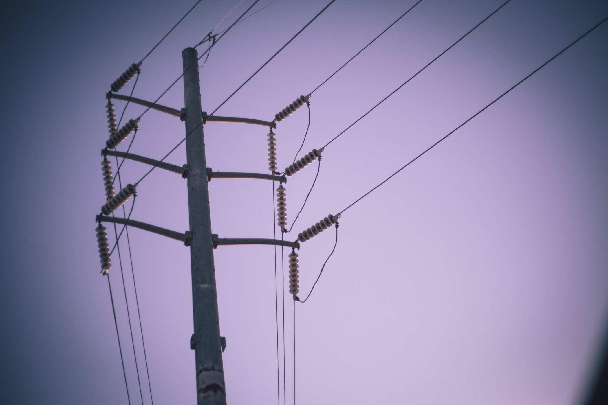 Photo of a large utility pole on a purple sky