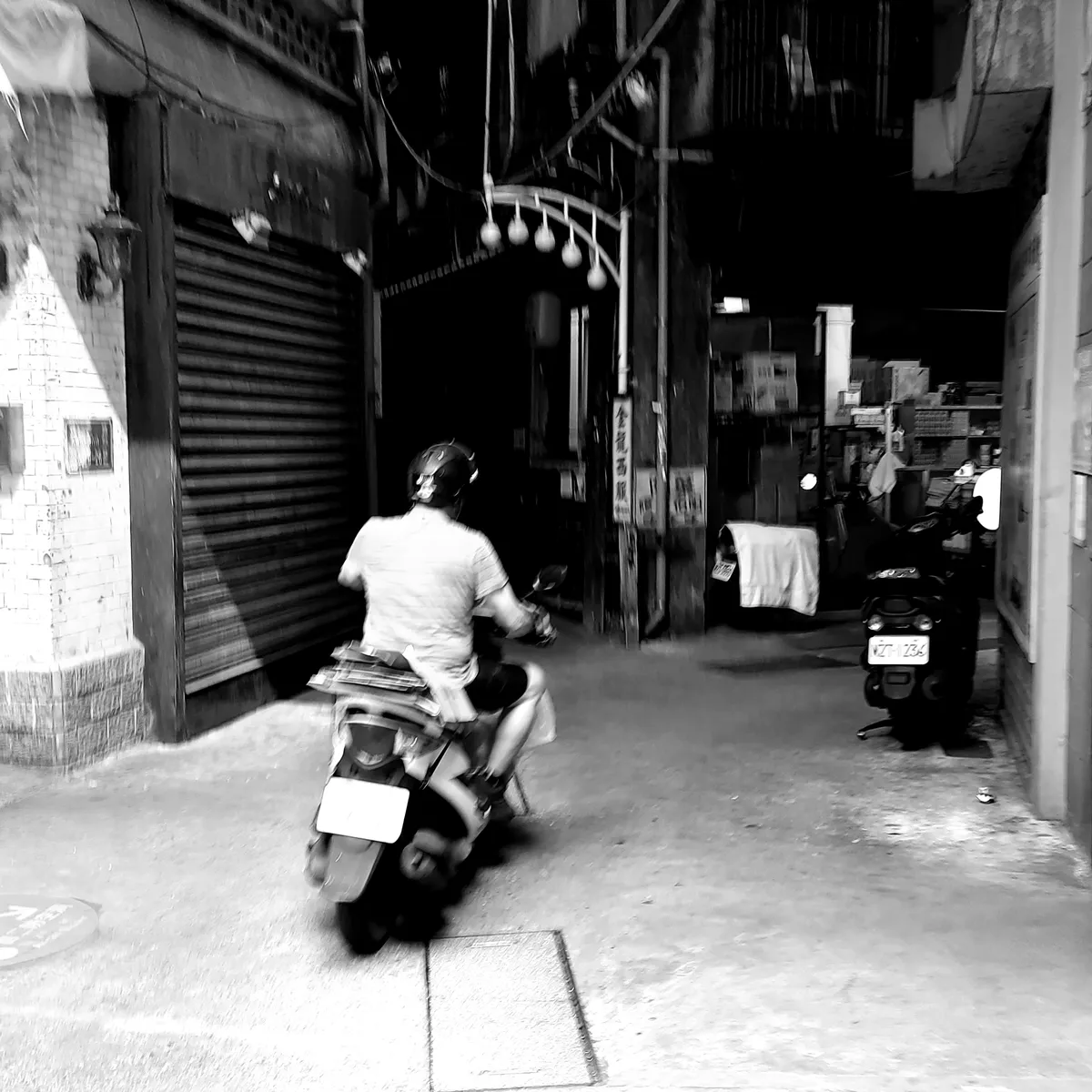 Man on a scooter turning into a covered alleyway