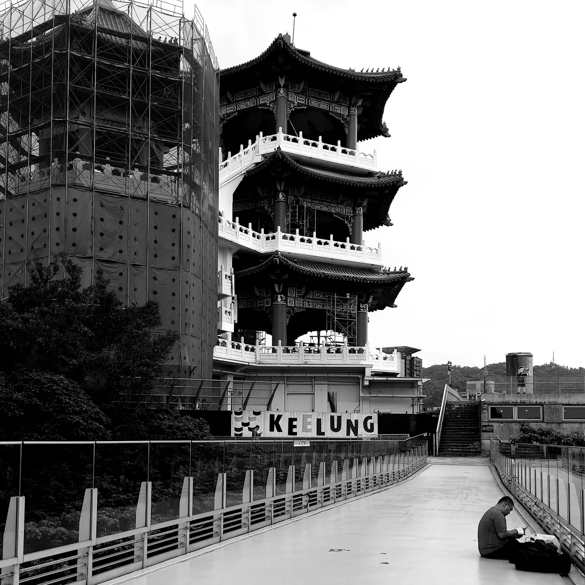 Man sitting alone in the shadow of a temple tower
