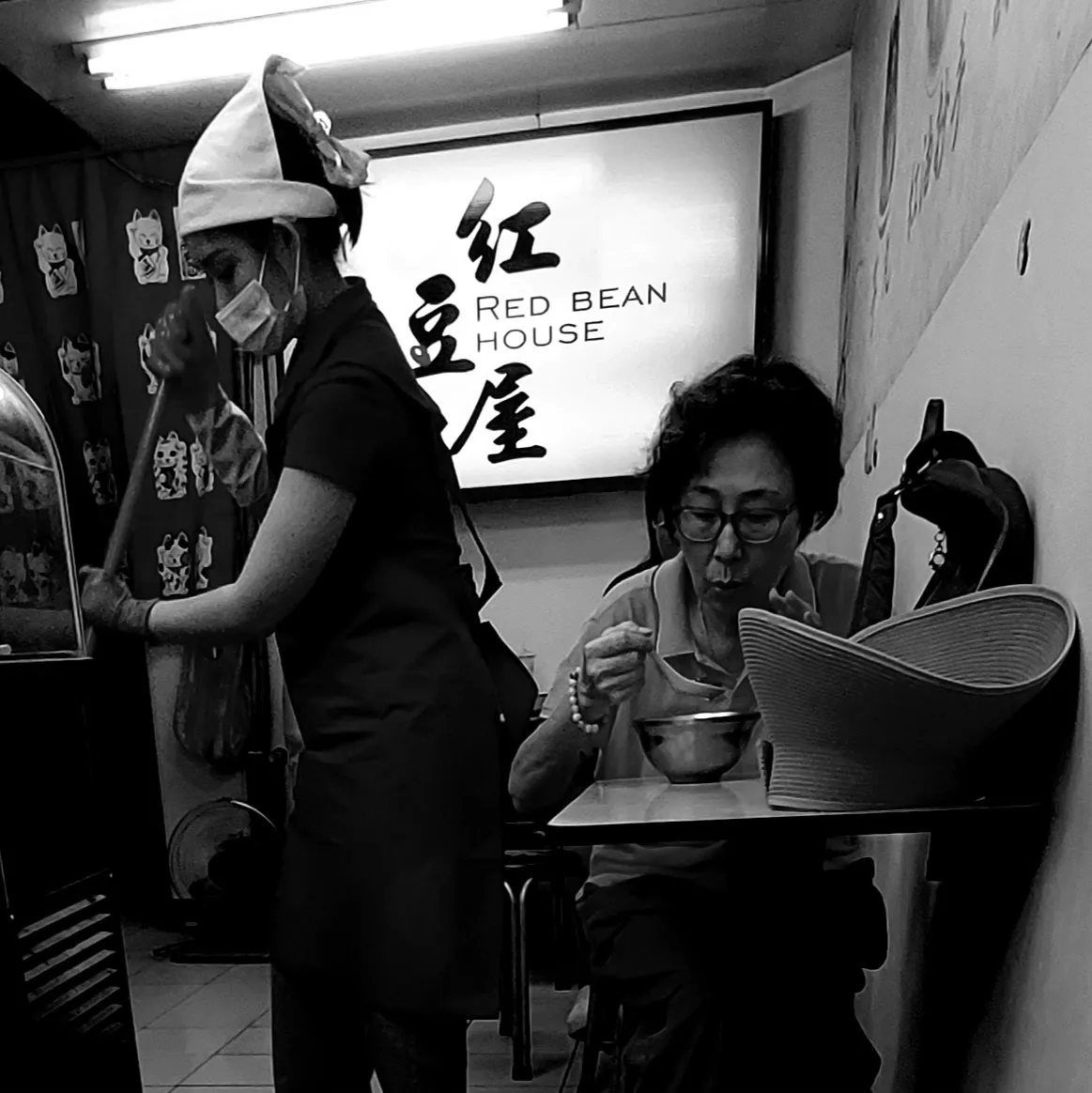 Woman eating alone while a staff member mops nearby