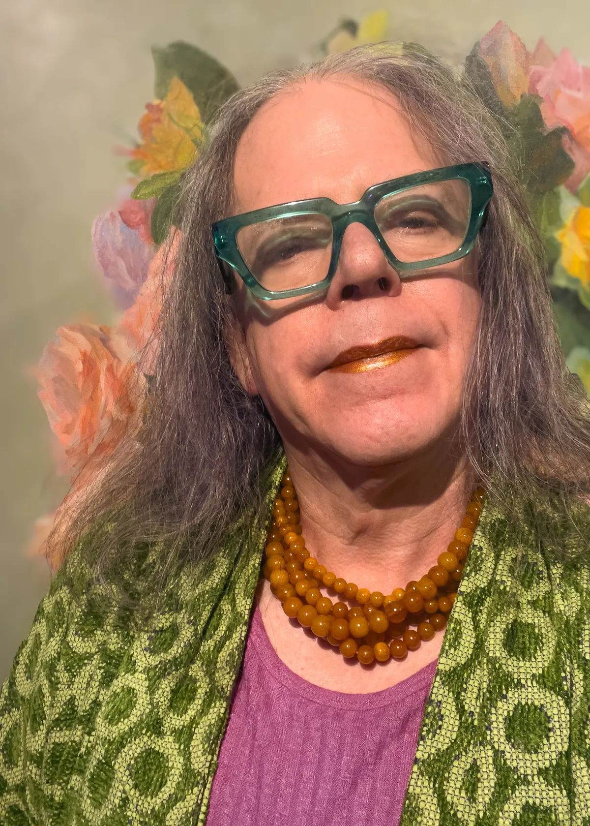 torso selfie with designer green jacket, pink dress, burn orange lipstick and necklace, hair down around shoulders, glasses 20251122-IMG_8721