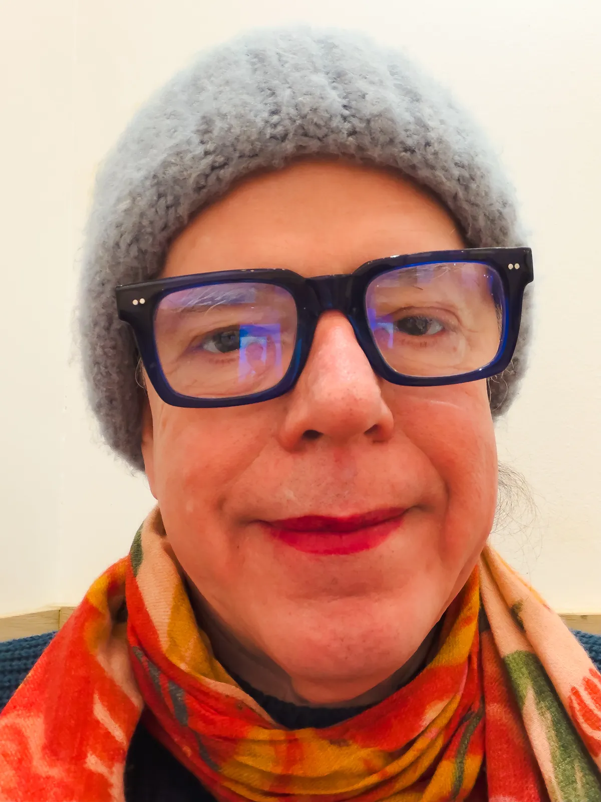 self portrait with blue knit cap, red patterned scarf, blue dress, blue frame glasses, red lipstick 20251215-IMG_9914