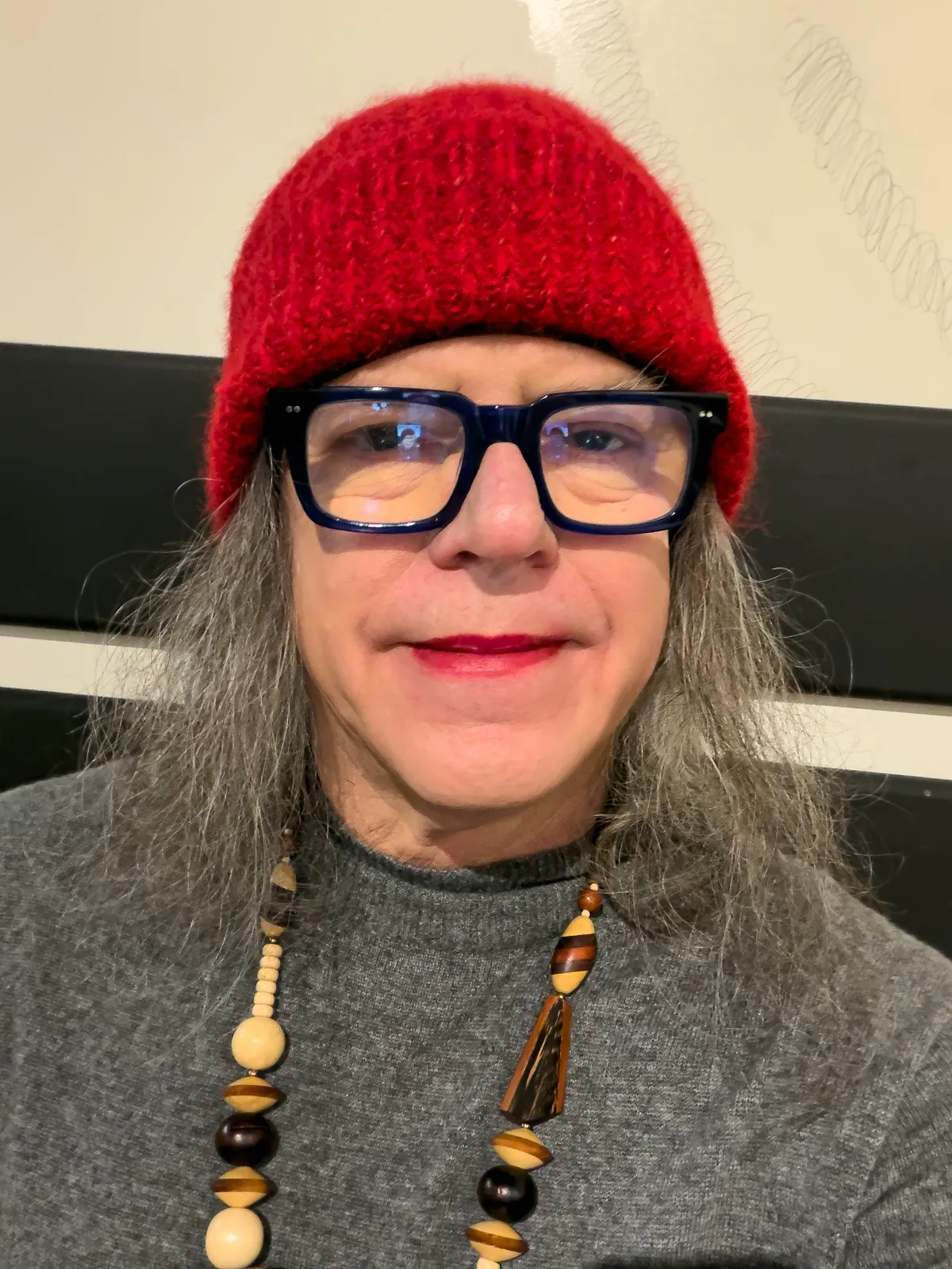 self portrait with red knit hat, red lipstick, blue frame glasses, wooden bead necklace, gray cashmere sweater dress 20260106-IMG_1194