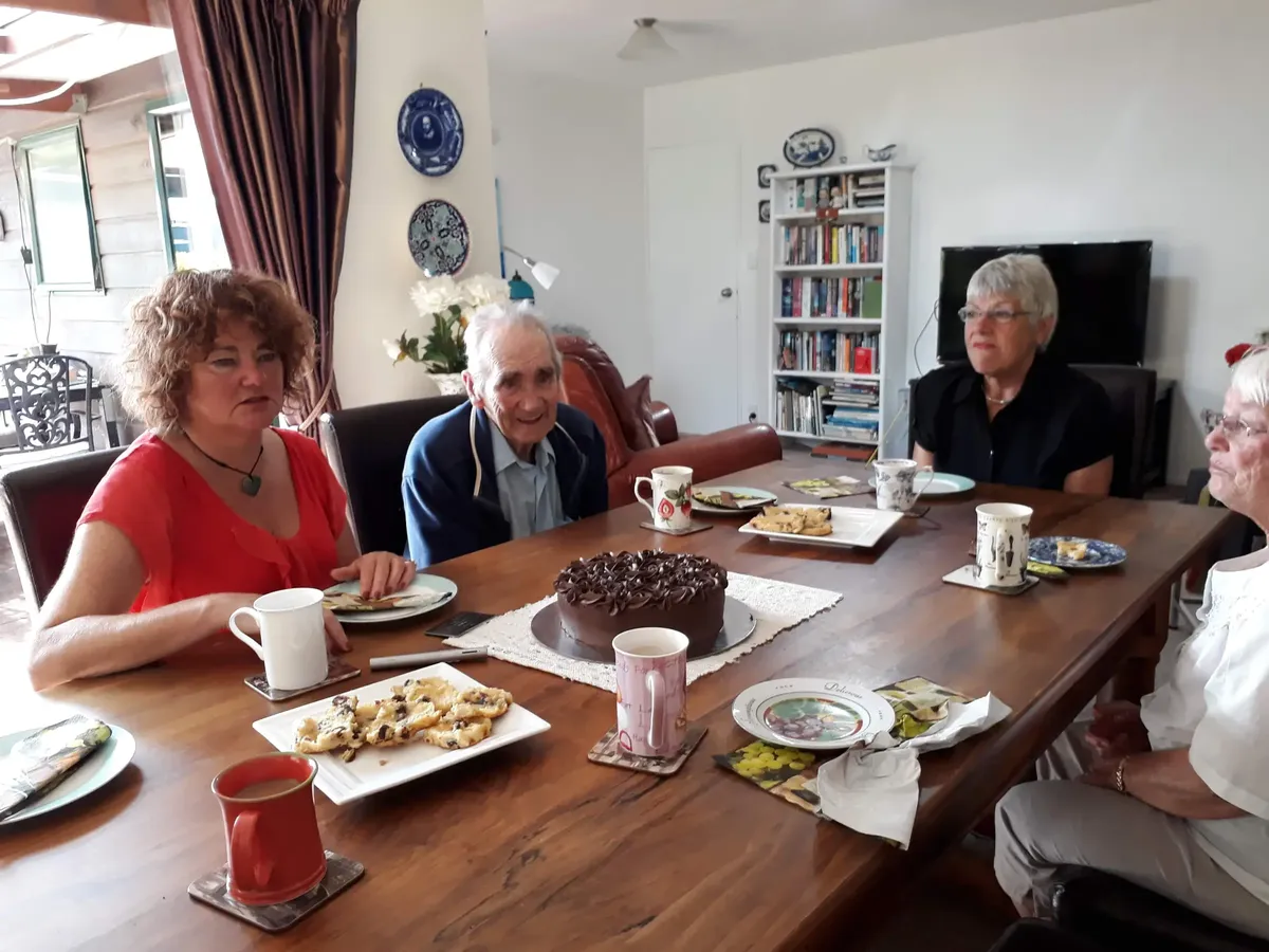 Group members sitting around table with coffee and cakes