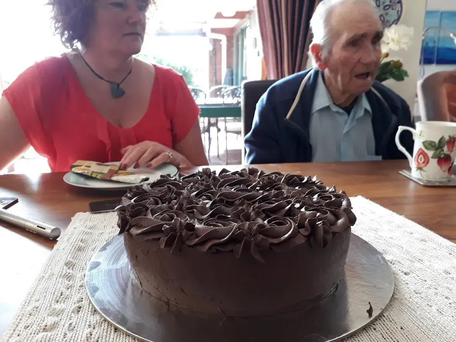 An amazing-looking chocolate cake, with network members in the background.