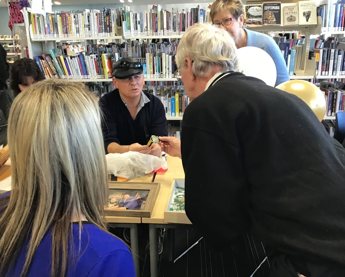 Bowler leaning across the table to show Dave his medals.