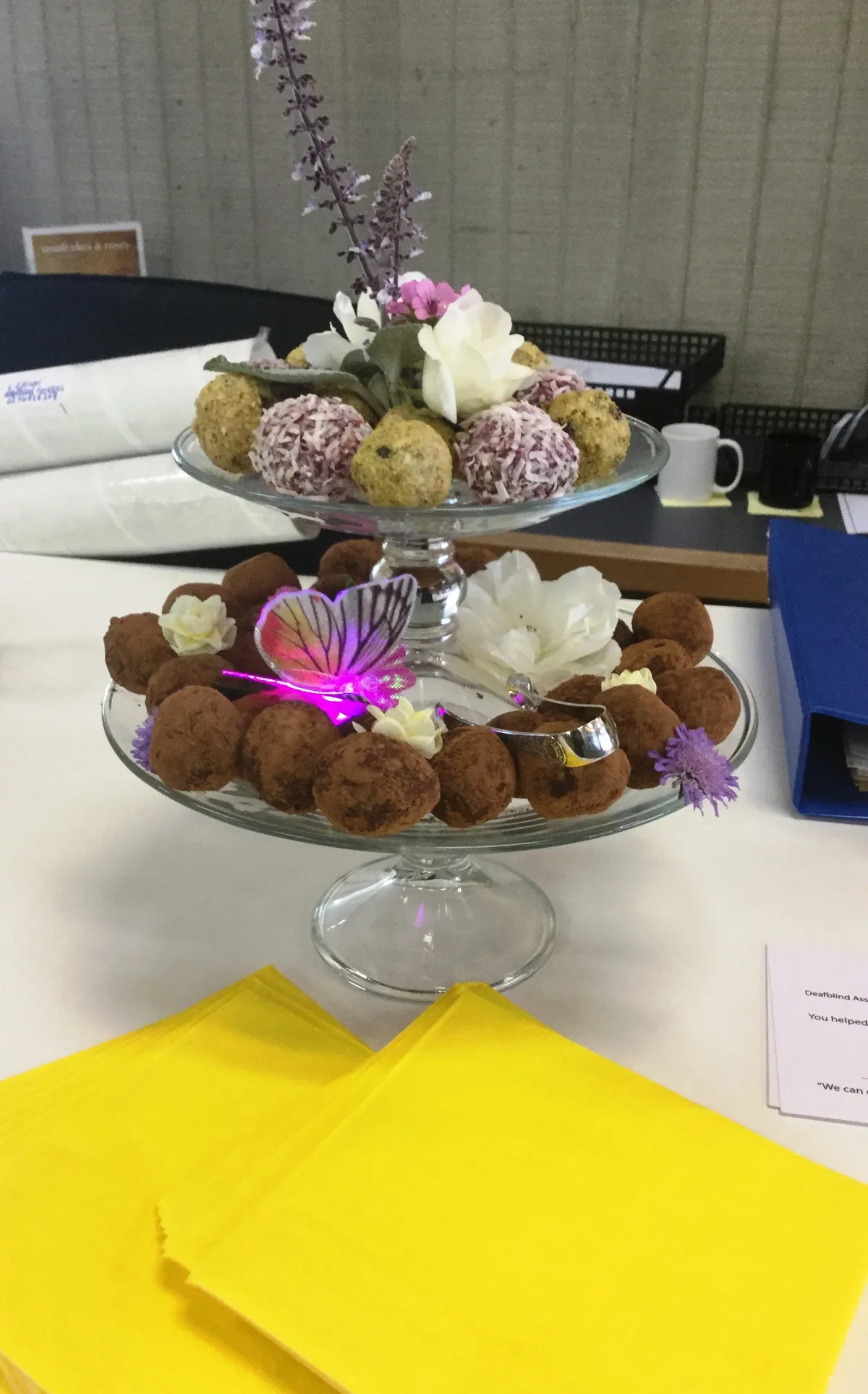 Gorgeous truffles arranged on a multi-layered tray, with flowers and a purple butterfly decoration.