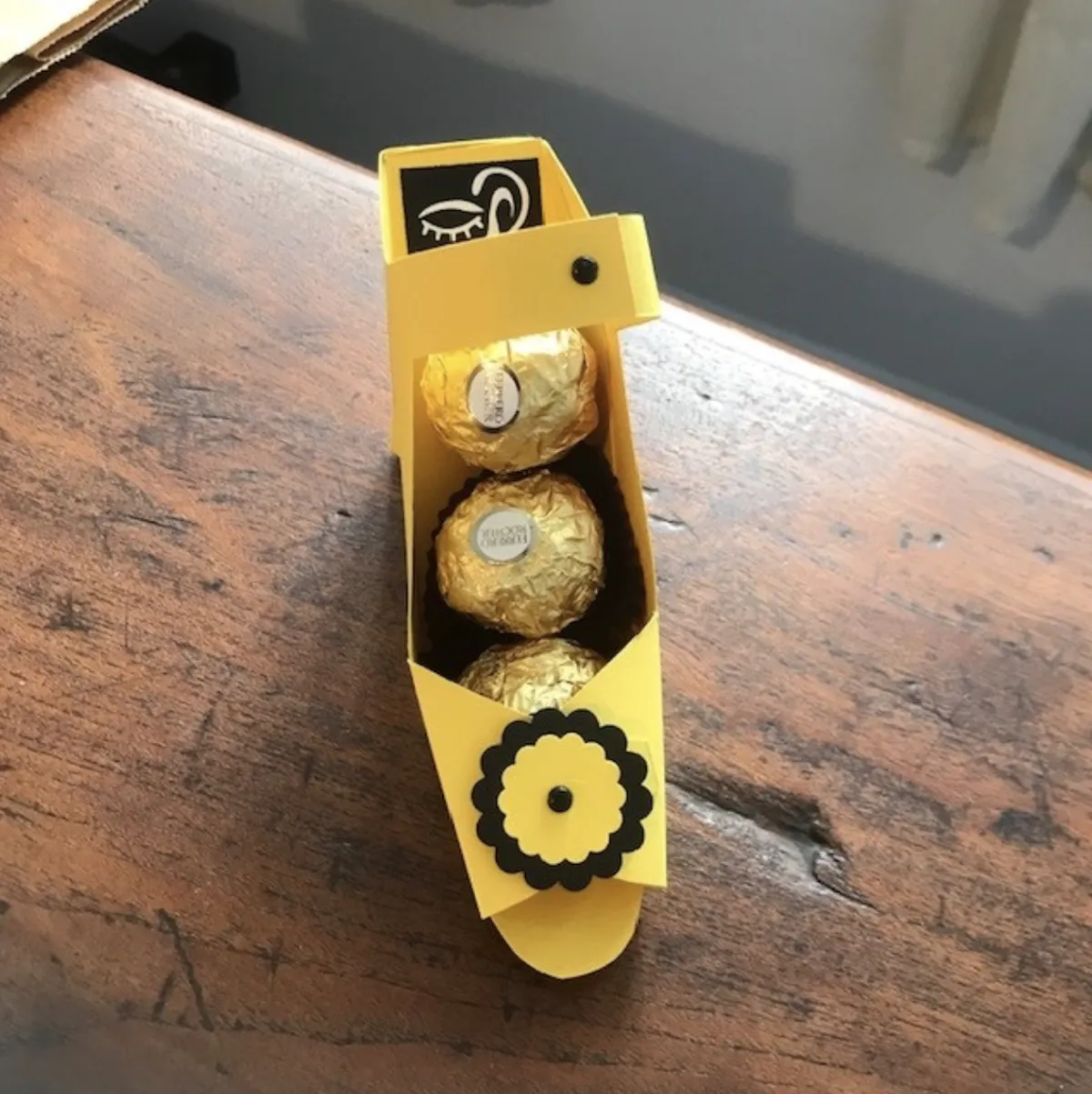 Ferrero Rocher chocolates in a yellow and black high-heeled sandal on which is the Deafblind Association NZ logo.