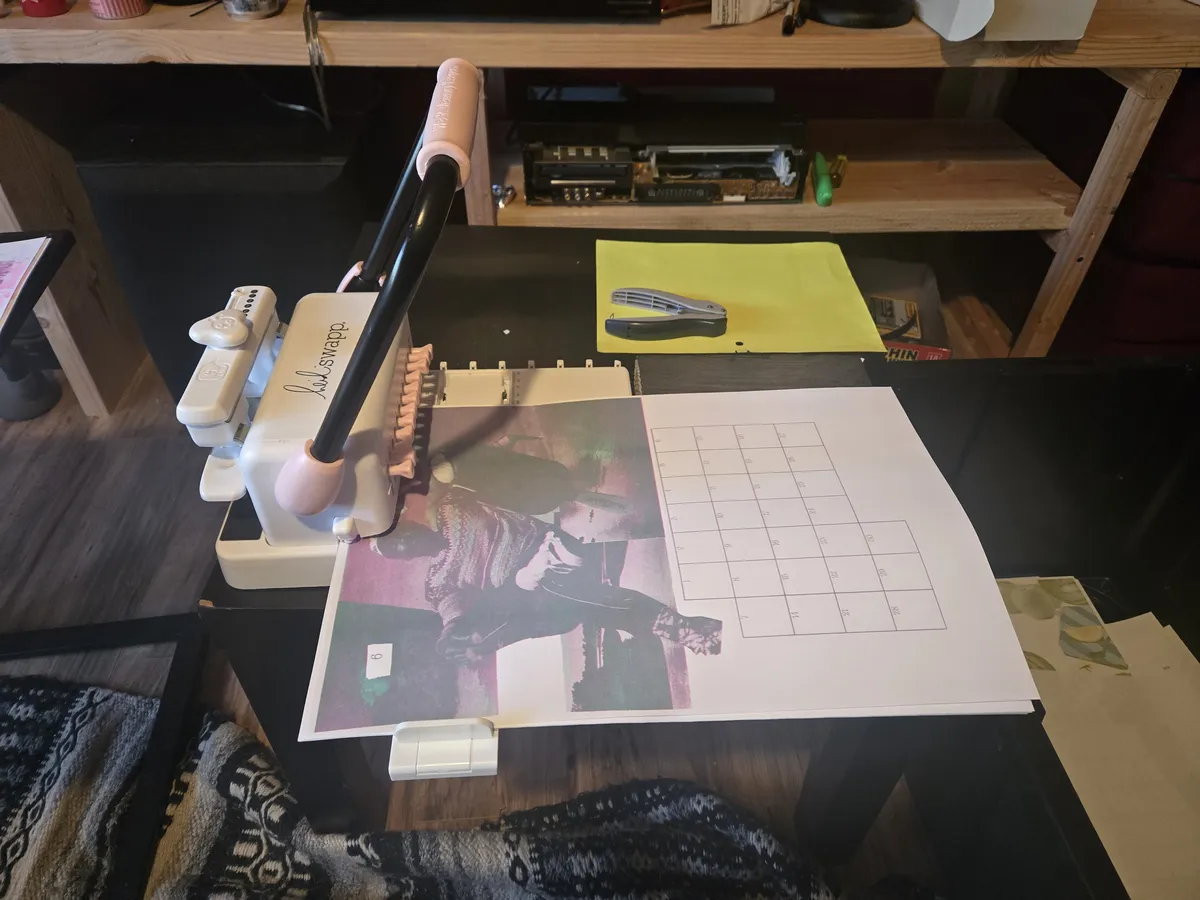 A wire binding machine with a calendar page inserted ready to be hole punched.