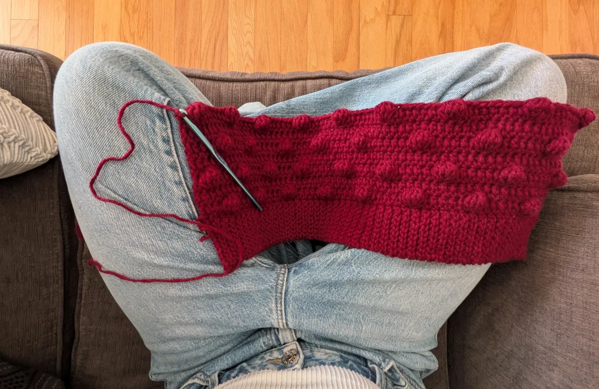 A few rows of a crochet project. The stitches alternate in a way that creates a textured polka dot effect.