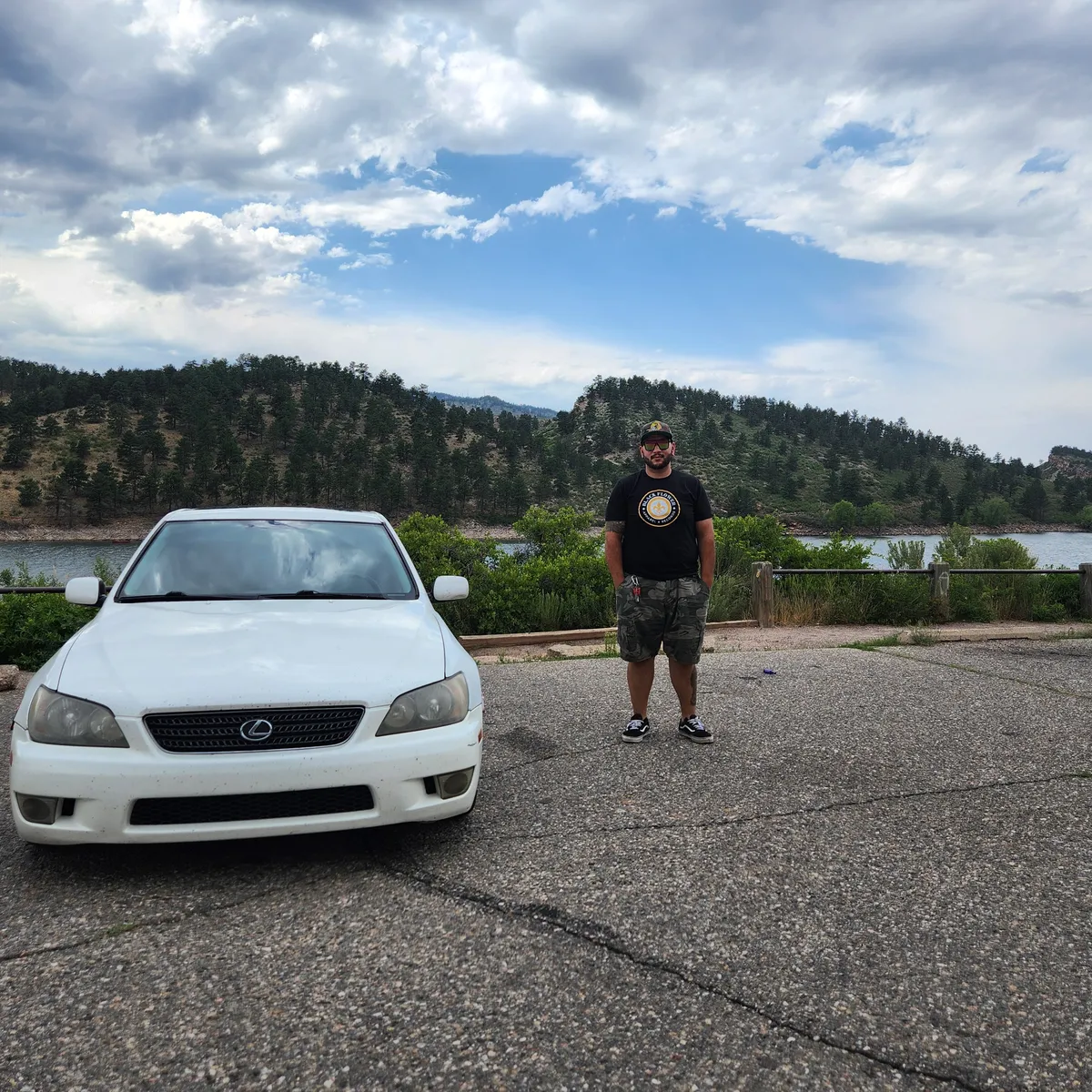 A man next to a white car with mountains