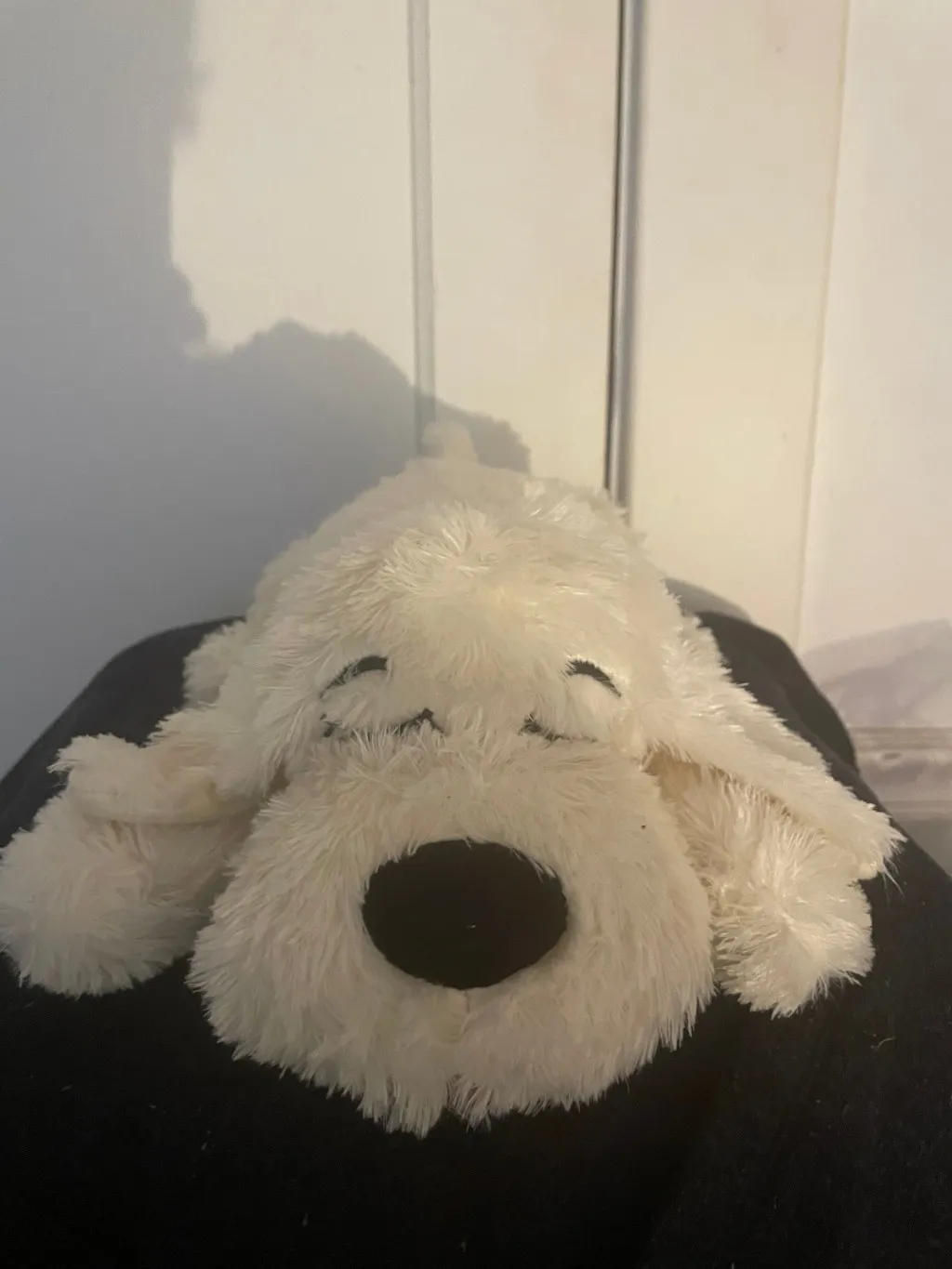 a white stuffed dog of unknown breed. fast asleep and laying on her stomach