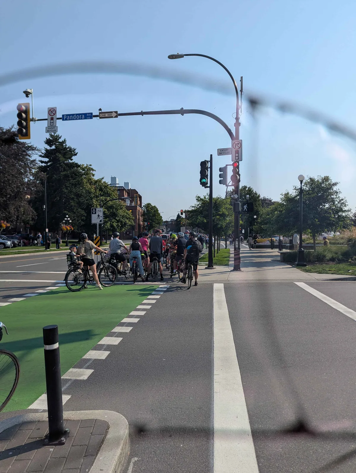 A picture of the bidirectional bike lane on Wharf St overflowing with people all trying to ride southbound. The last two people have toddlers in child seats on the back of their bikes.
