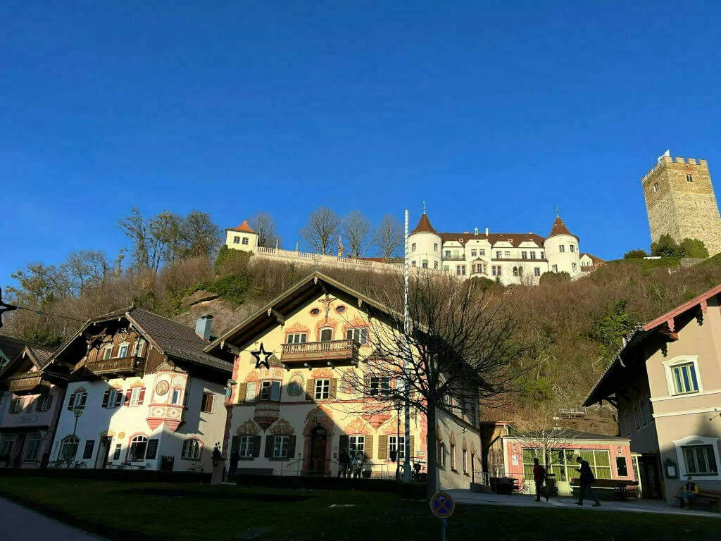Marktplatz mit traditioneller Lüftlmalerei an den Fassaden und Blick hoch zu Schloss Neubeuern.