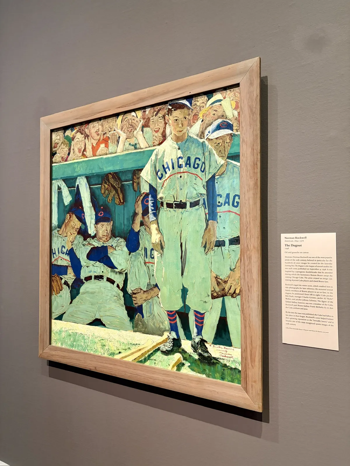 Ein gemaltes Kunstwerk zeigt mehrere Baseballspieler in einer Umkleidekabine. Ein Spieler steht im Vordergrund, gekleidet in ein weißes Trikot mit der Aufschrift 