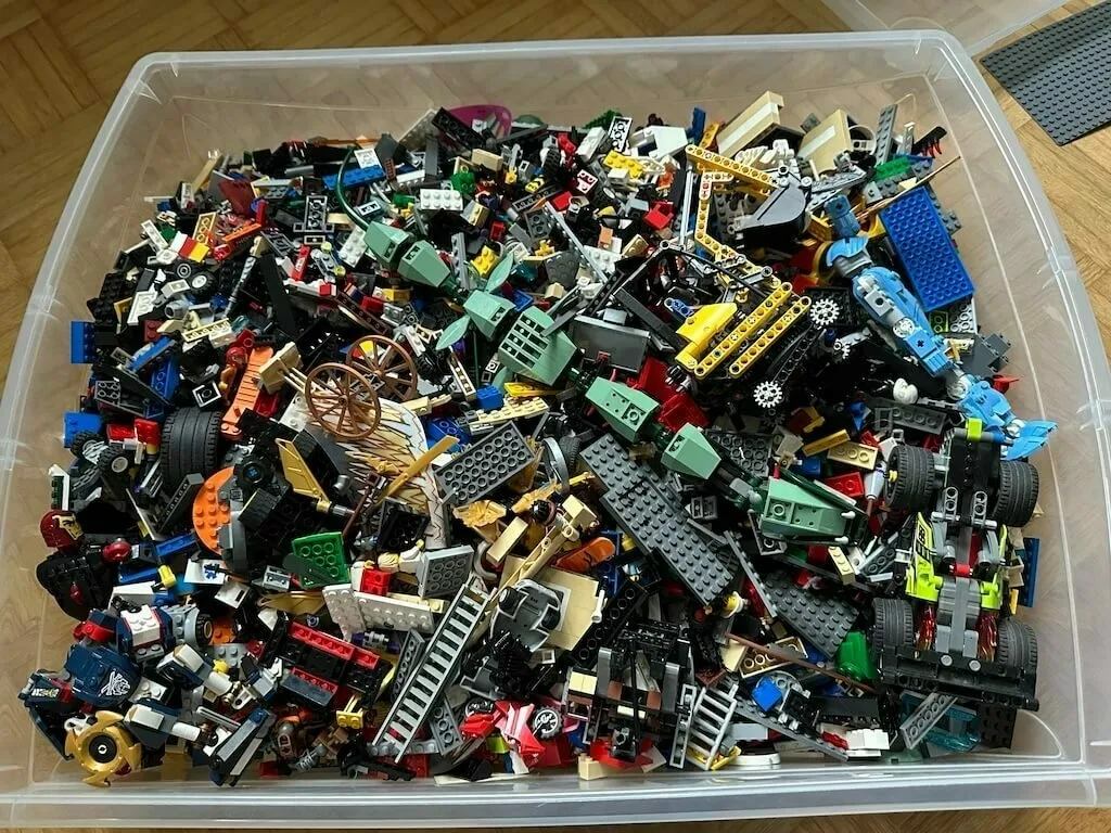 Eine große Plastikkiste mit jeder Menge Lego steht in einem Zimmer.