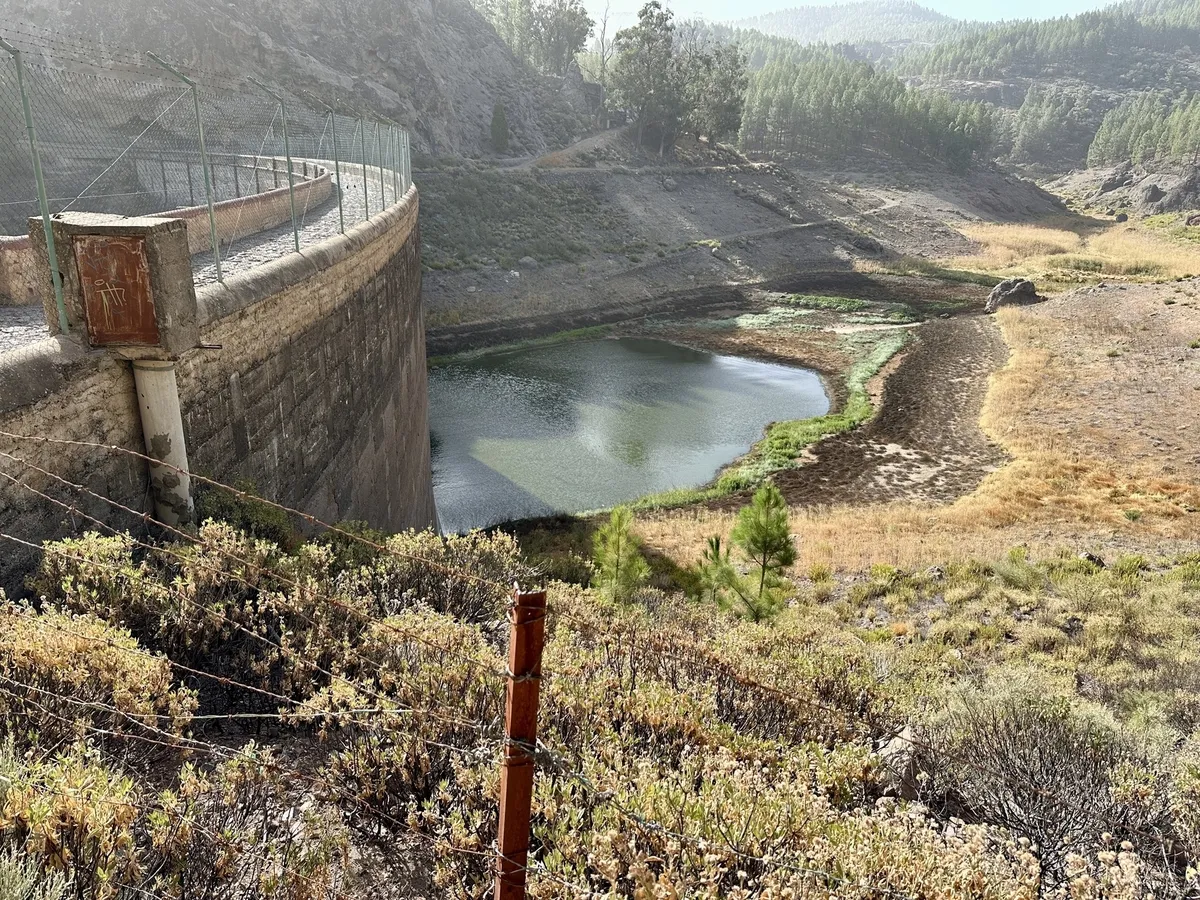 Der Stausee Presa de los Hornos ist von trockenen Landschaften und Vegetation umgeben, wobei der Wasserspiegel niedrig erscheint.
