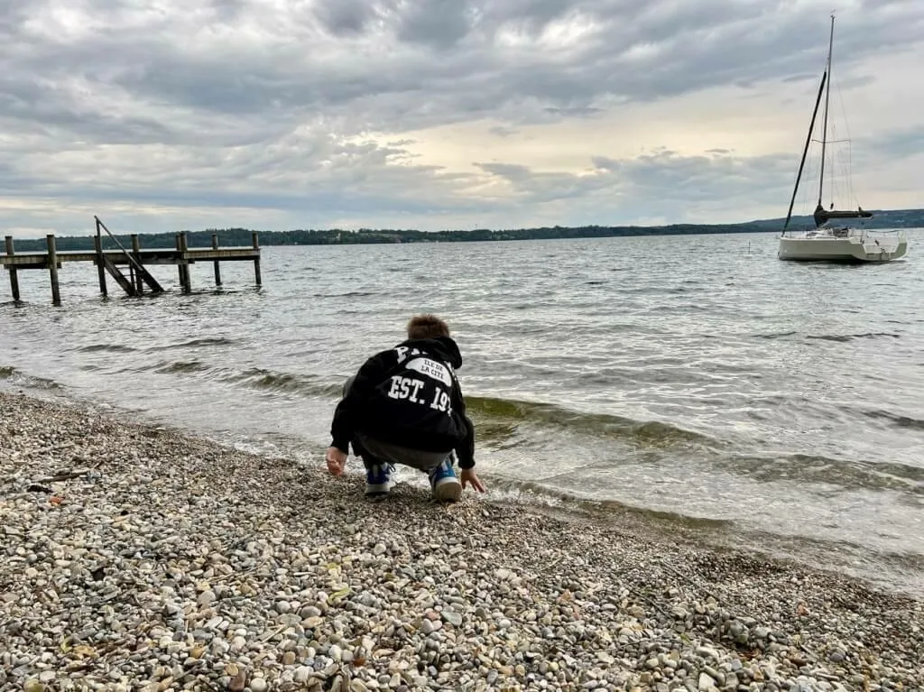 Der 11-Jährige wirft Steine in den Starnberger See.