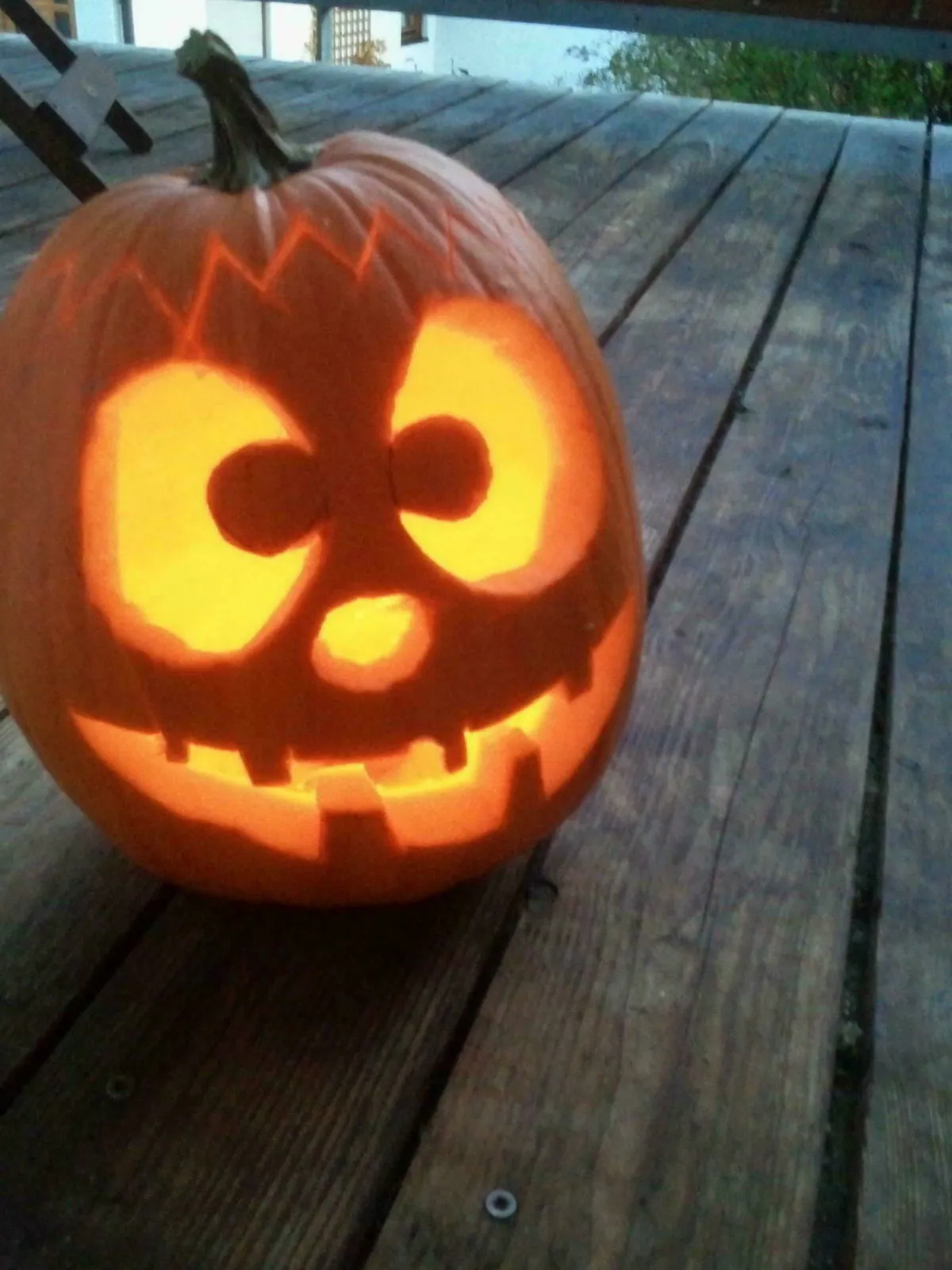 Ein freundliches Gesicht in einem Kürbis, auf einem hölzernen Balkon