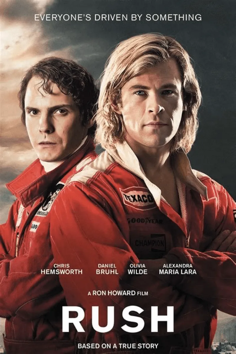 Filmplakat für den Film Rush (2013). Es zeigt die Hauptdarsteller Chris Hemsworth (rechts, mit langen blonden Haaren) und Daniel Brühl (links, mit dunklen Haaren) in roten Rennfahreranzügen. Über ihren Köpfen steht der Slogan "EVERYONE'S DRIVEN BY SOMETHING". Am unteren Rand sind die Namen der Hauptdarsteller und der Filmtitel RUSH, untertitelt mit "BASED ON A TRUE STORY", zu sehen.