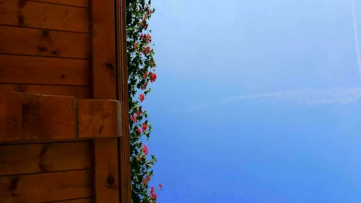 Schöner Ausblick unter einem Holzbalkon mit Geranien in den blauen Himmel