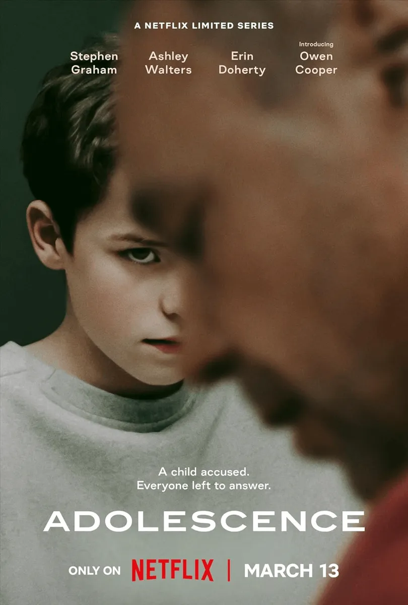 Filmposter für die Netflix-Miniserie „Adolescence“. Es zeigt das ernste Gesicht eines jungen Jungen, der teilweise von einer unscharfen Figur im Vordergrund verdeckt wird.
