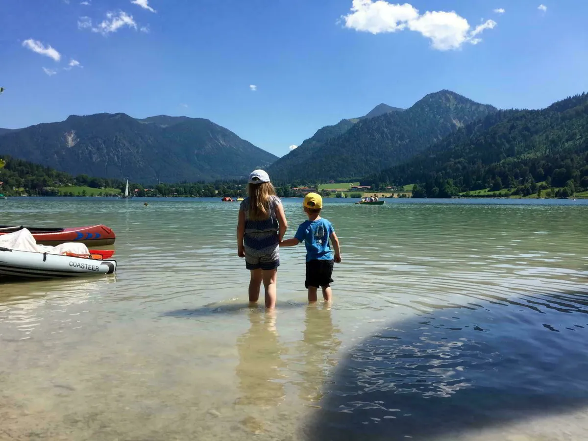 Kinder stehen Hand in Hand im Wasser vom Schliersee