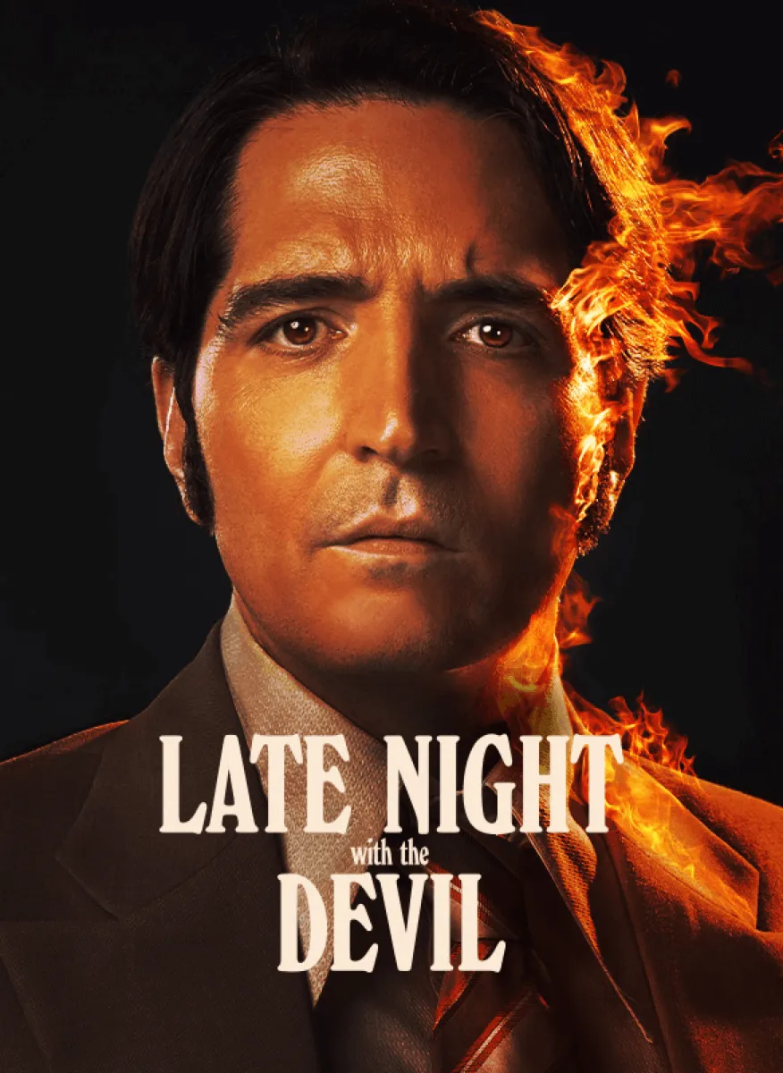 Ein Mann in einem Anzug, dessen Gesicht zur Hälfte von Flammen umgeben ist, schaut ernst und konzentriert.