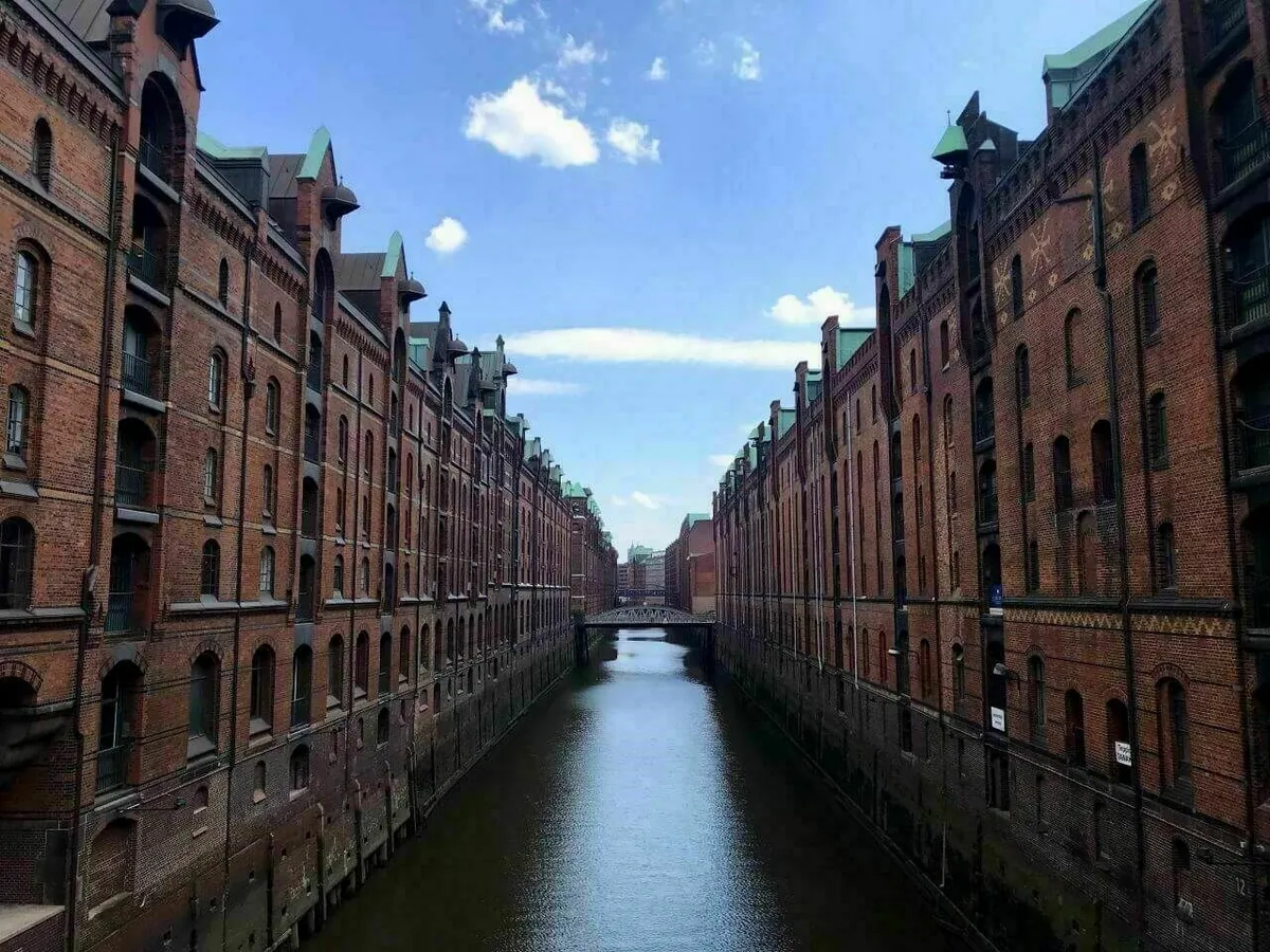 Die historischen Speicherstadt in Hamburg mit den charakteristischen roten Backsteingebäuden und Kanälen, die sich im Wasser spiegeln.