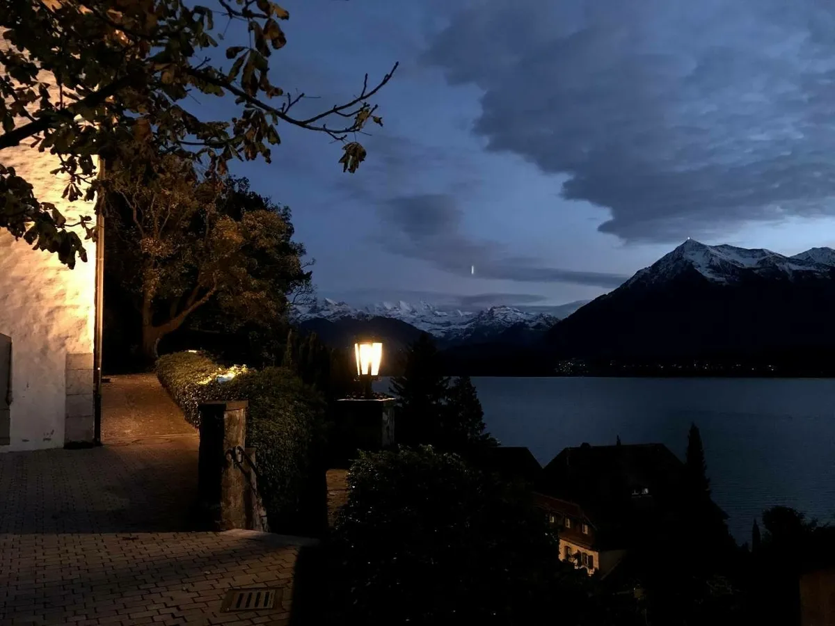 Blick über den abendlichen Thuner See auf die verschneiten Berge
