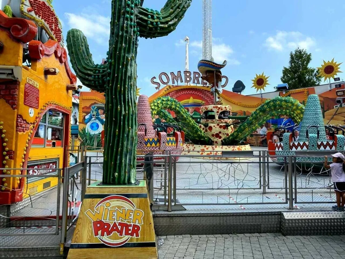 Das Fahrgeschäft "Der Sombrero" auf dem "Wiener Prater". Im Vordergrund steht eine große, dekorative Kaktusfigur.