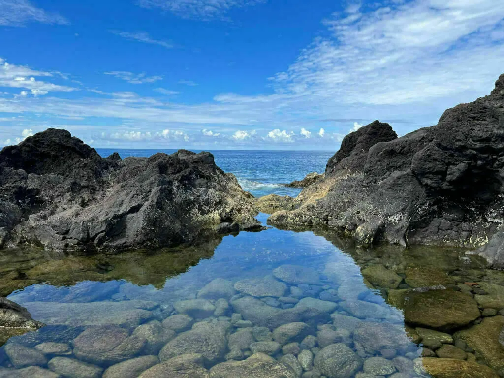 Lava direkt am Strand der Azoren mit einer hübschen Spiegelung im Wasser.
