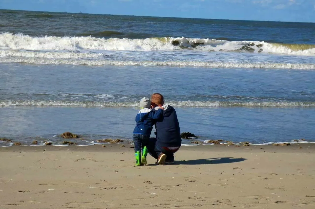 Vater und Sohn schauen vom Strand aus auf die holländische Nordsee
