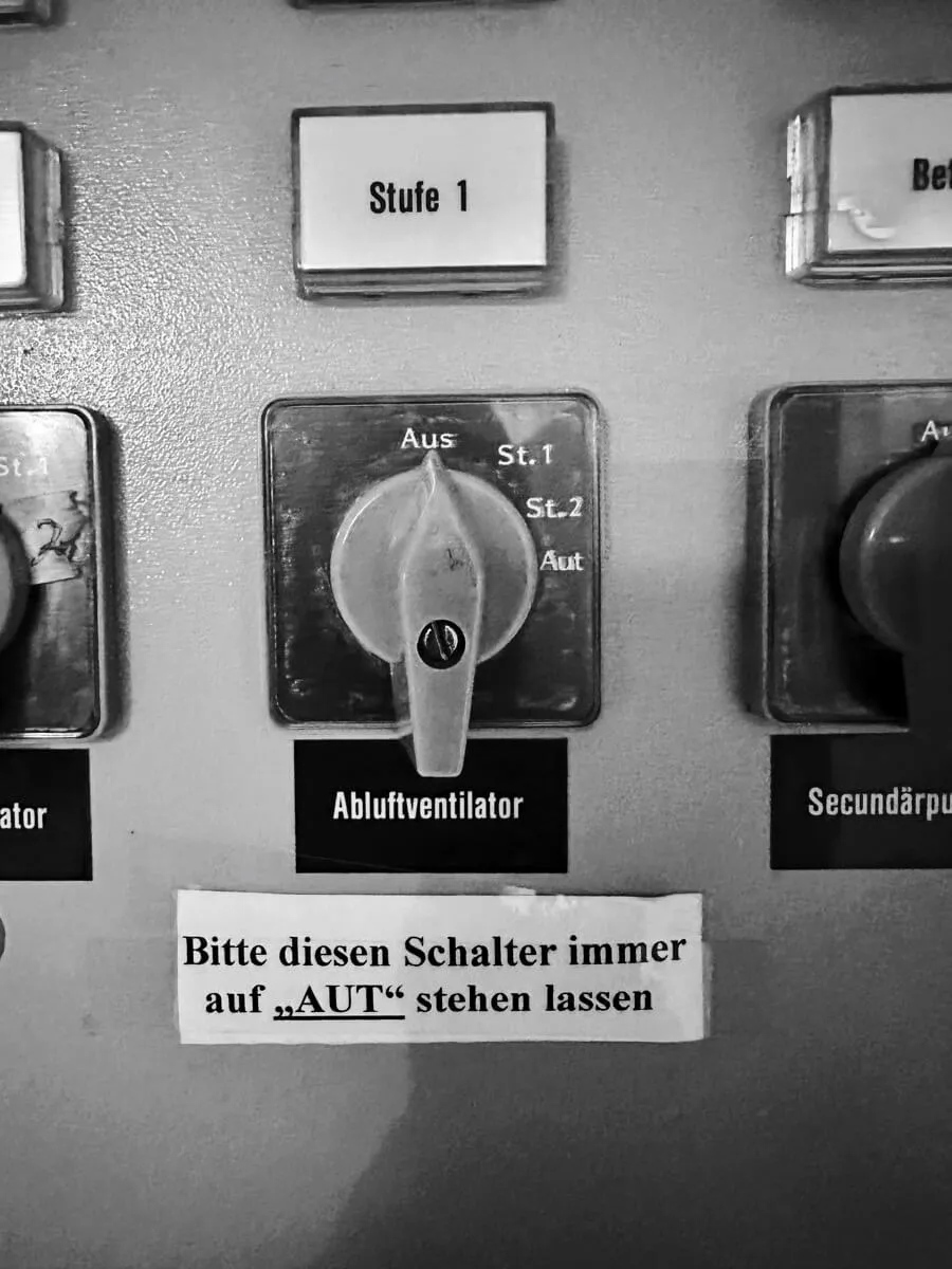 Ein Schaltpult mit Drehschaltern, wobei einer für einen Abluftventilator mit den Einstellungen Aus, St.1, St.2 und Aut beschriftet ist.