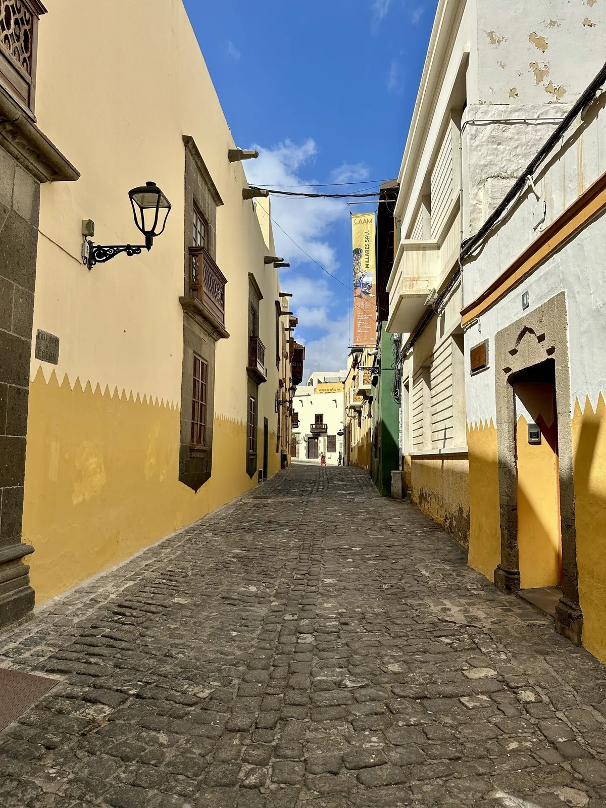 Eine ruhige, gepflasterte Straße ist von bunten, historischen Gebäuden umgeben.