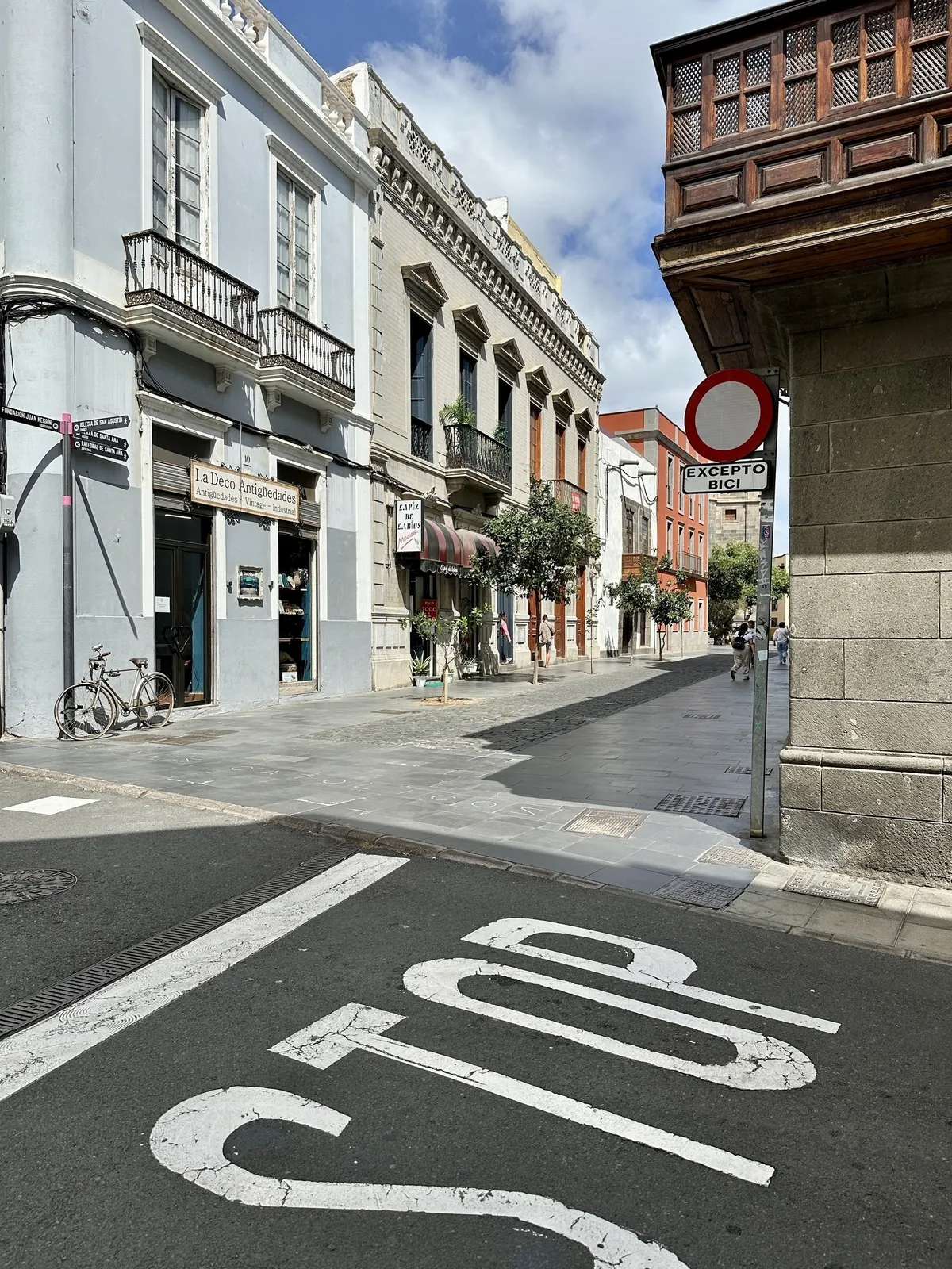 Eine ruhige, sonnige Straße in einer Stadt mit historischen Gebäuden, einem Stoppschild auf der Straße und einem Verkehrsschild mit spanischem Text.