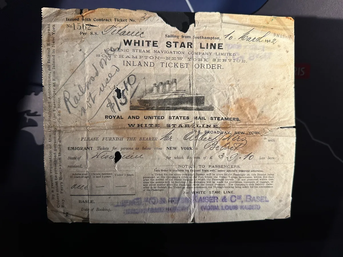 Ein altes Ticket der White Star Line für die Überfahrt auf der Titanic ist abgebildet, mit handschriftlichen Notizen und Stempeln versehen.