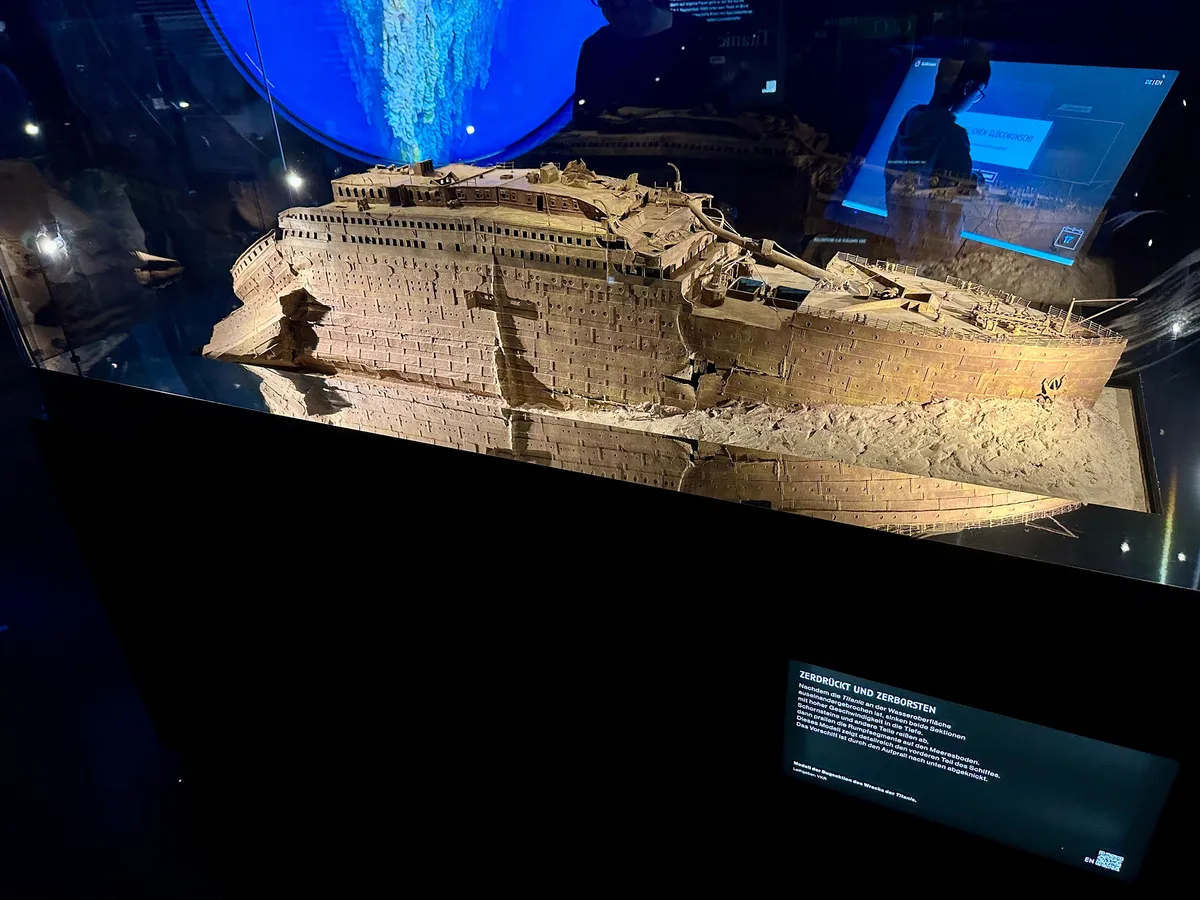 Ein Modell des beschädigten Schiffsrumpfs der Titanic, ausgestellt in einem beleuchteten Vitrinenschrank, ist zu sehen.