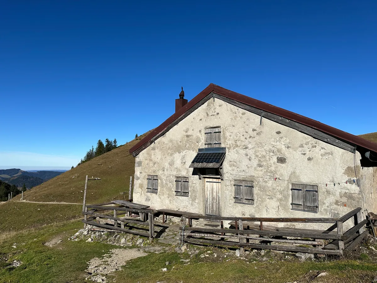 Die geschlossene Jägerbauernalm auf  einem Hügel unter einem klaren blauen Himmel.